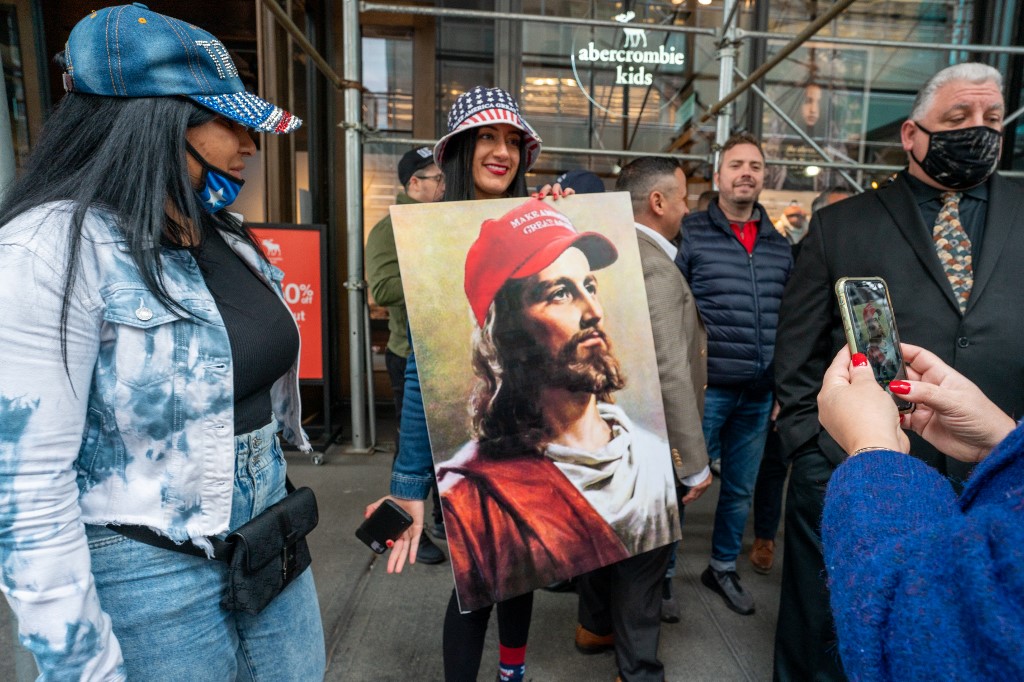 Woman with a painting of Jesus wearing a 'Make America Great Again' baseball cap at a rally for Donald Trump in New York City, October 25 2020 (AFP)