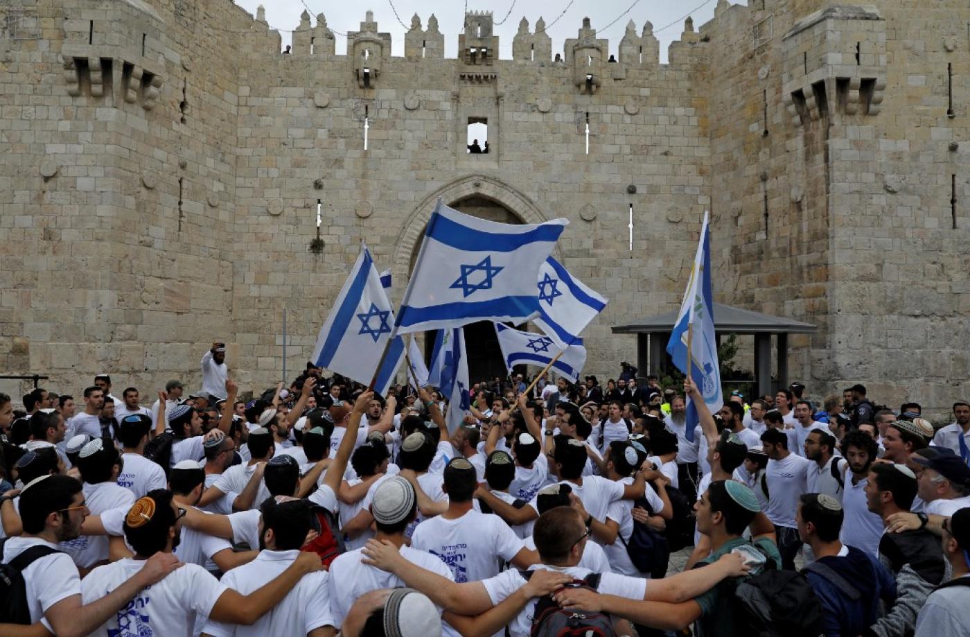 Des colons agitent des drapeaux israéliens alors qu’ils célèbrent la Journée de Jérusalem au niveau de la porte de Damas de la vieille ville, en mai 2018 (AFP)