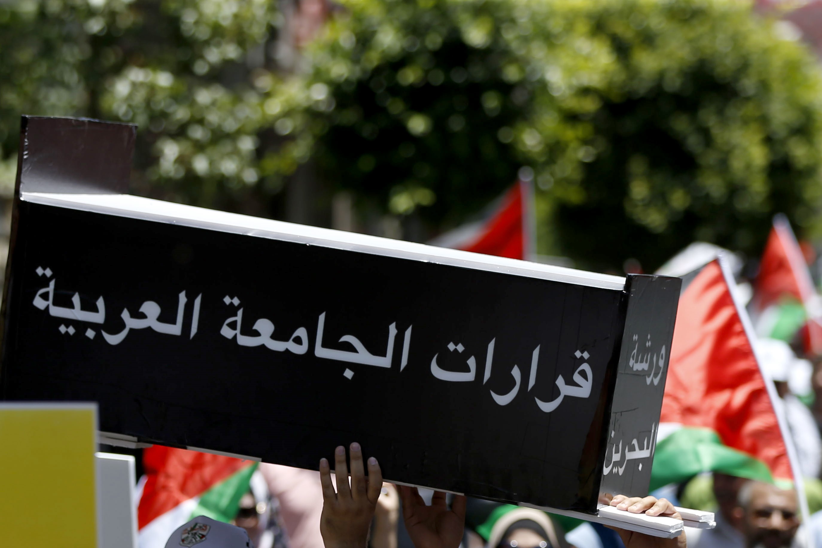Palestinian demonstrators carry a makeshift coffin with the inscription "the decisions of the Arab League" during a protest against the US-led Peace to Prosperity conference that opens tomorrow in Bahrain, in the Israeli