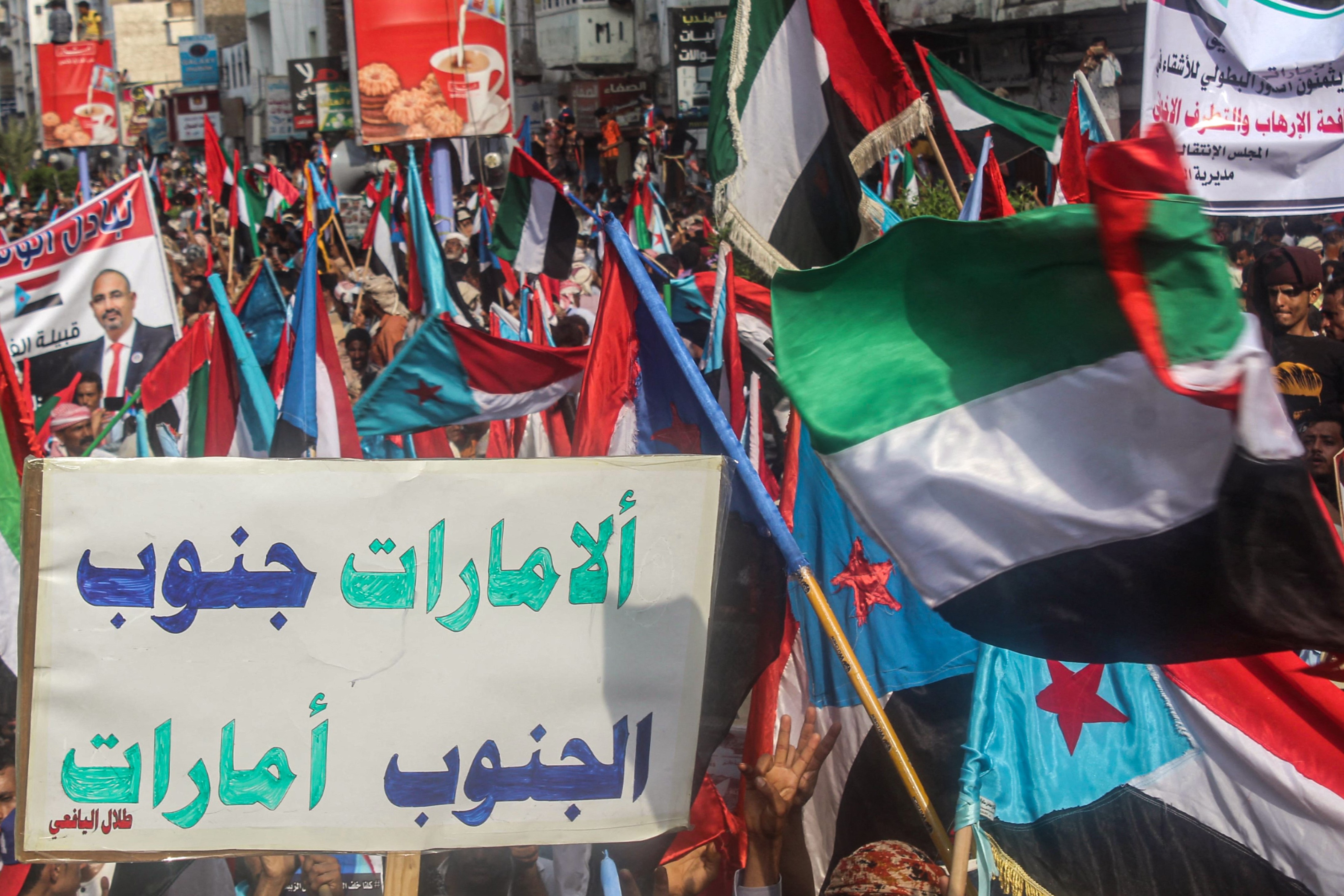 People march with a sign reading in Arabic "UAE South, South UAE" with the flags of south Yemen and the United Arab Emirates (UAE) during a demonstration titled the "million-man march of gratitude for Saudi Arabia and the UAE", in the centre of the second city of Aden on September 5, 2019.