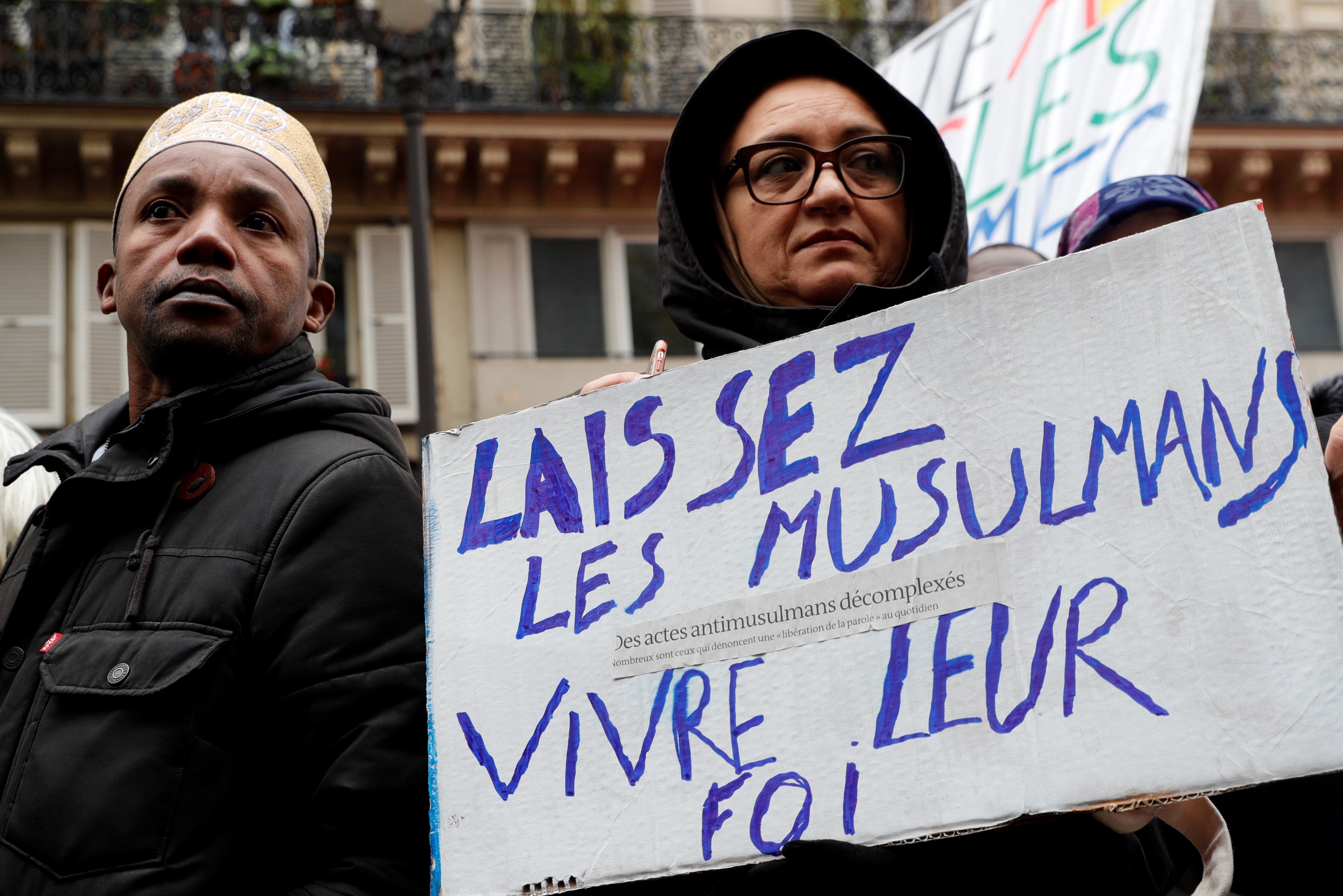 A woman holds a placard reading "Let Muslims live their faith" as she takes part in a demonstration march in front of the Gare du Nord, in Paris to protest against Islamophobia, on November 10, 2019.