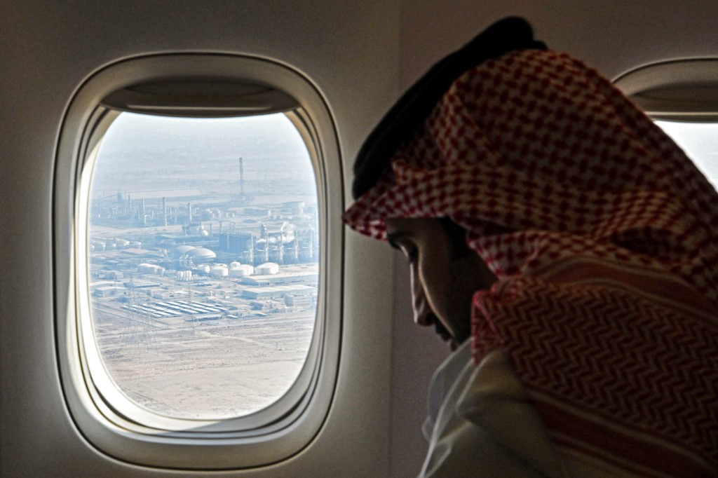 A man sits in a plane with the porthole showing an aerial view of oil industrial facilities at Jubail Industrial City in eastern Saudi Arabia, the world's top oil exporter. (Afp)