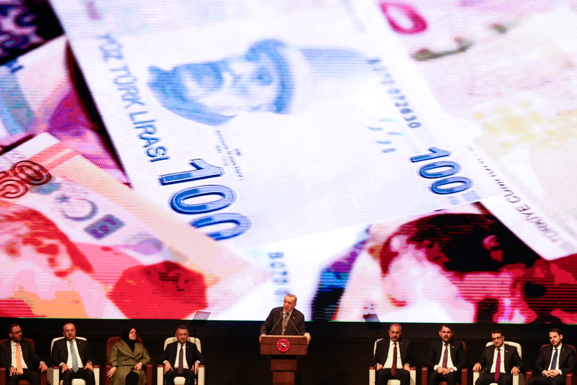 Turkish President Recep Tayyip Erdogan gestures as he delivers a speech on stage, with on the background banknotes of the Turkish lira (AFP)