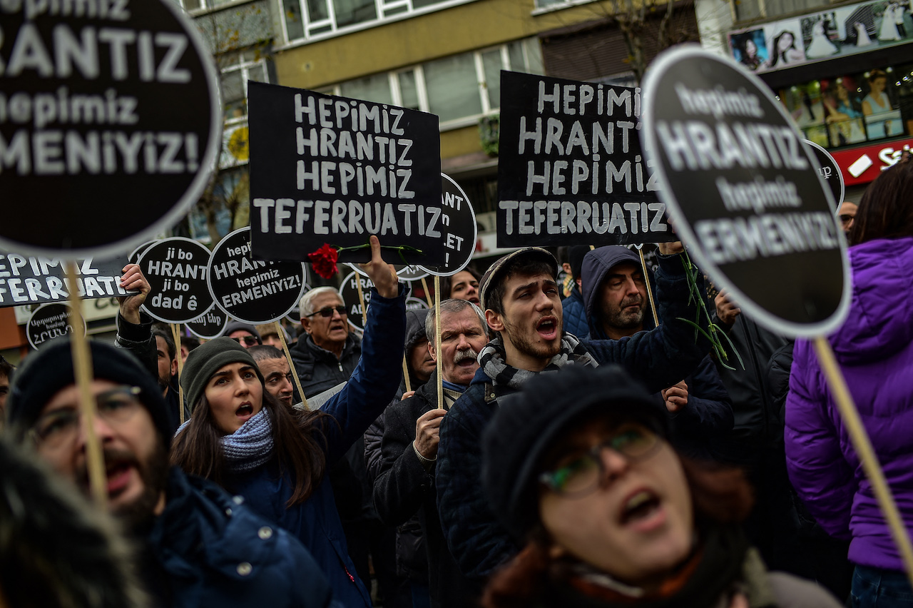 People hold placards, some of them reading "Justice for Hrant, we are all Armenian", in front of the offices of Armenian weekly newspaper Agos in Istanbul on January 19, 2020 (AFP)