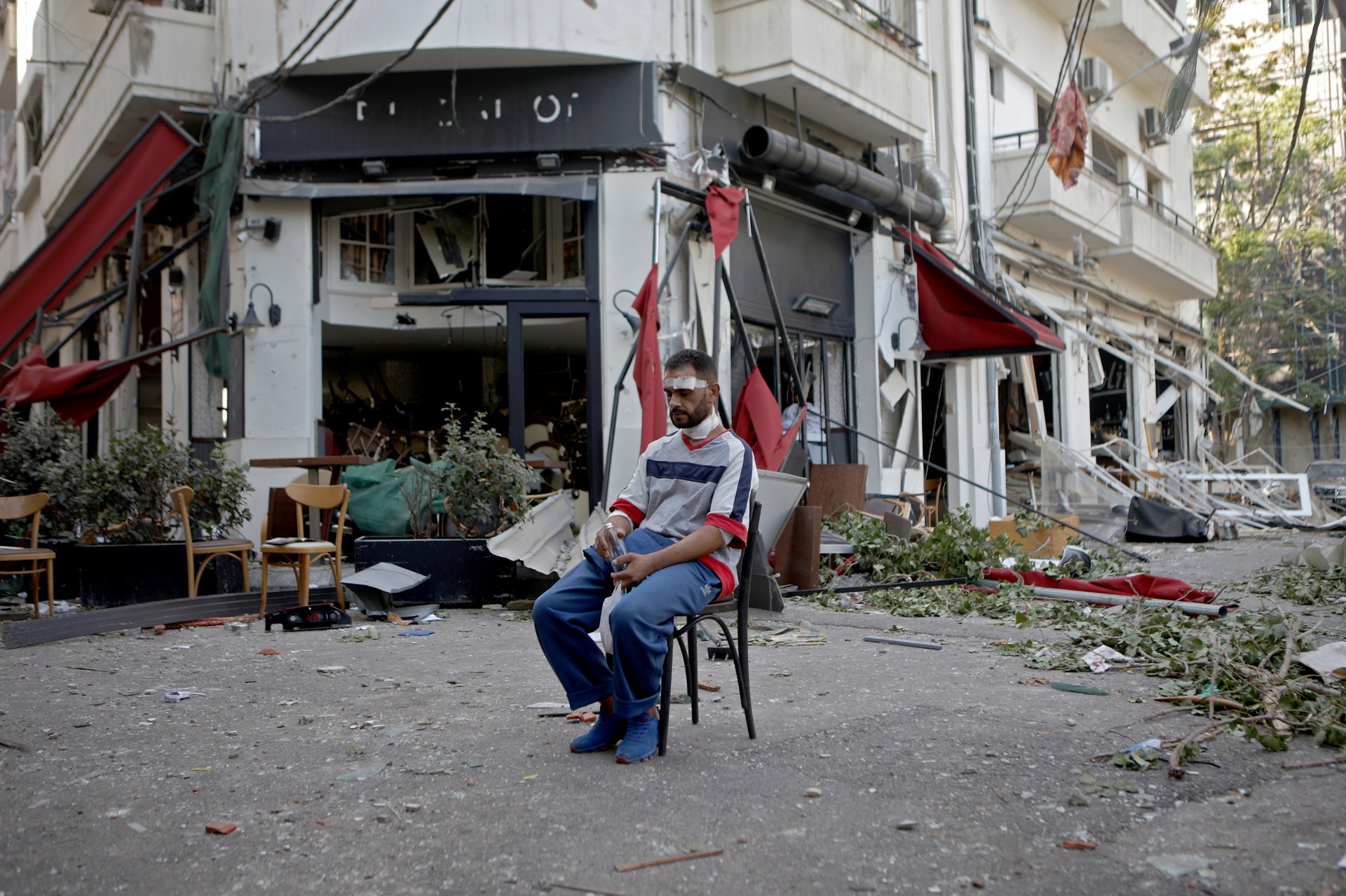 An injured man sits next to a restaurant in the trendy partially destroyed Beirut neighbourhood of Mar Mikhael (AFP)