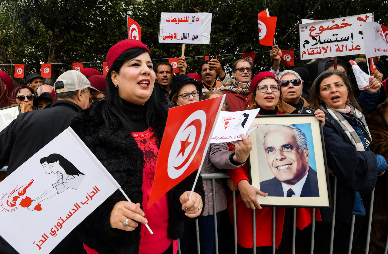 Abir Moussi, president of Tunisia's Free Destourian Party (Free Constitutional Party) shouts slogans as another colleague holds up a portrait of late president Habib Bourguiba during a protest against the Truth and Dignity Commission (TDC) outside its closing conference in the capital Tunis on December 14, 2018. The Truth and Dignity Institute