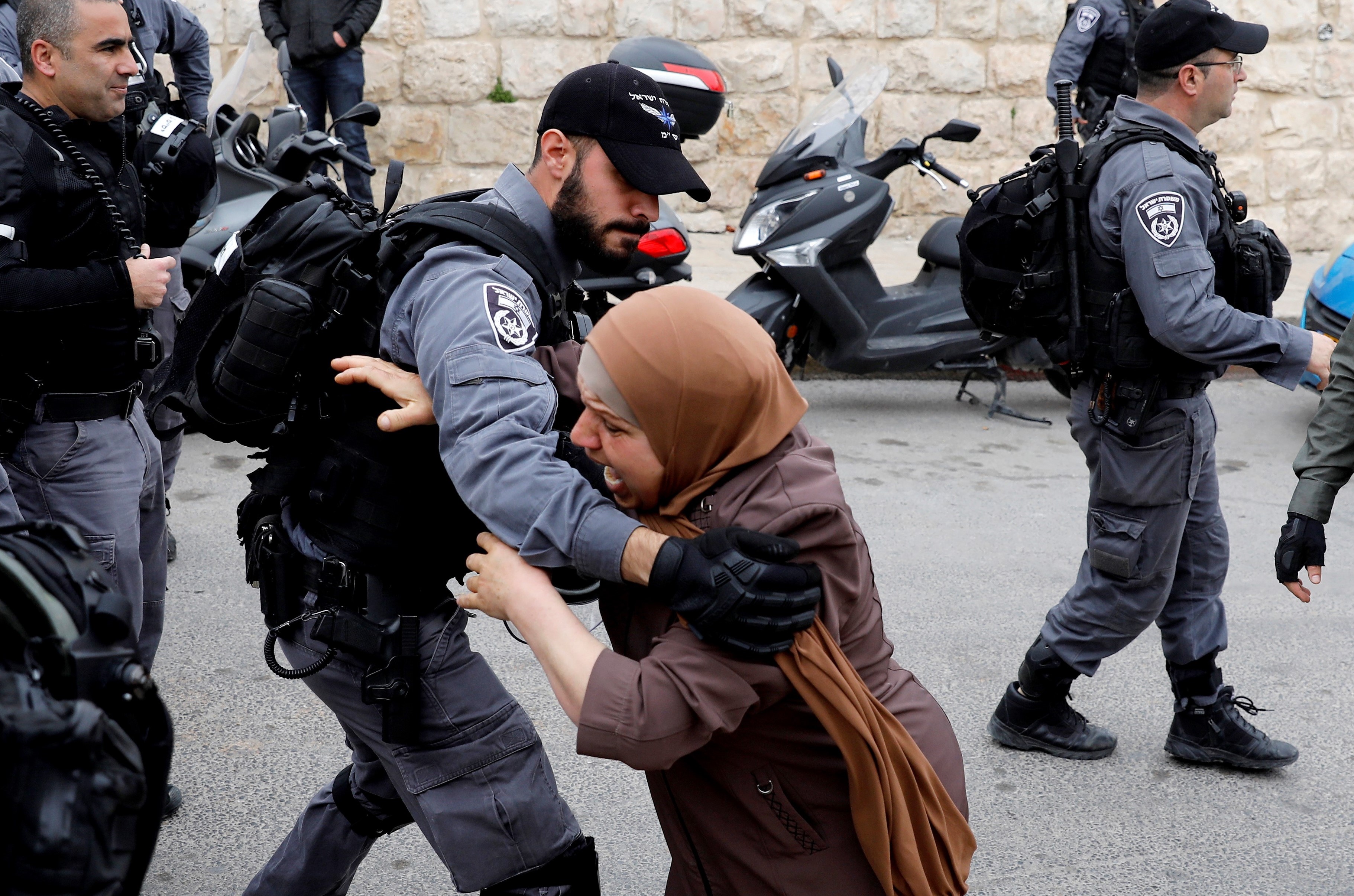An Israeli policeman pushes back a Palestinian woman outside the Old City of Jerusalem after Israeli forces closed the entrance to al-Aqsa mosque compound on 12 March (AFP)