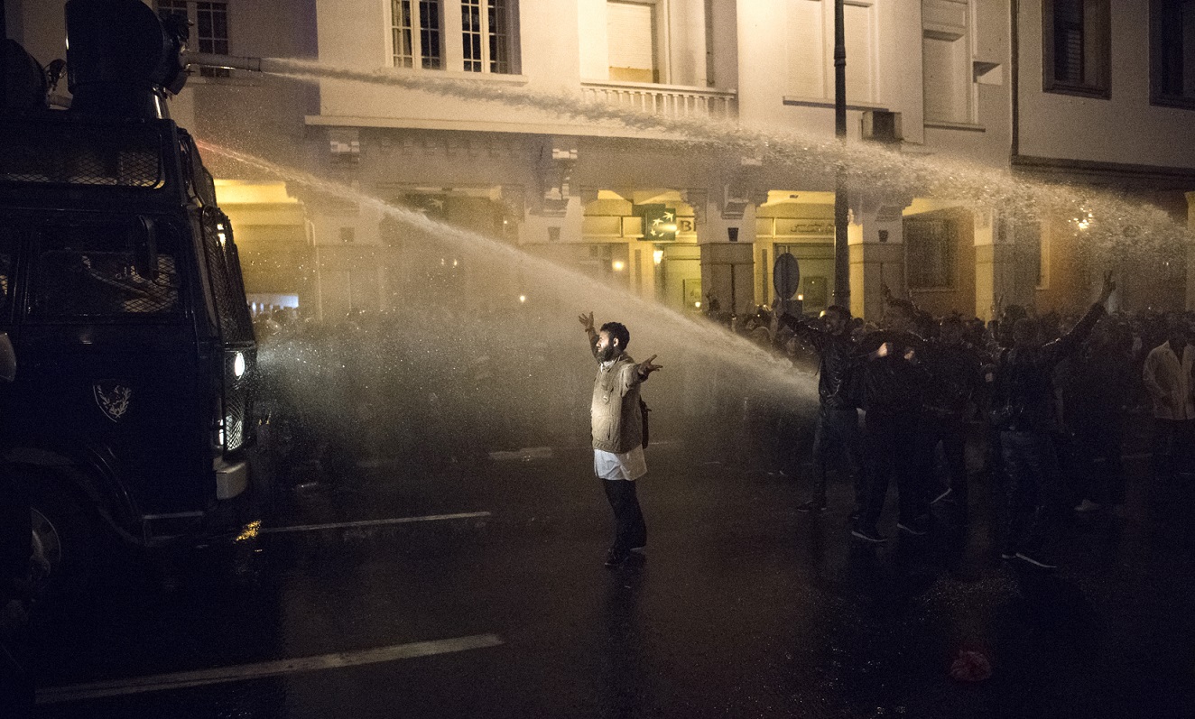 Un manifestant fait face aux canons à eau déployés par la police lors d’une manifestation des enseignants à Rabat, le 24 mars 2019 (AFP)