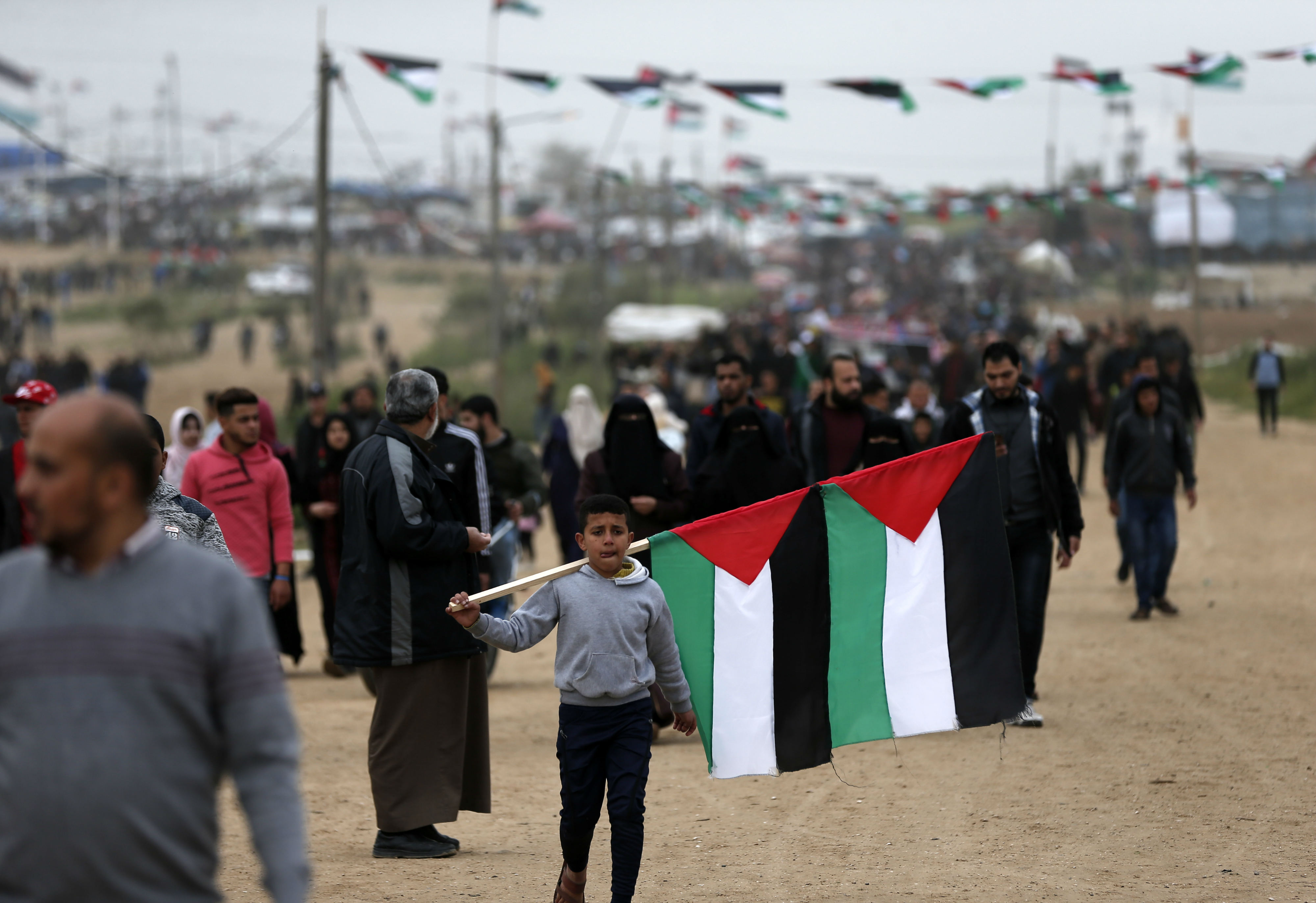 A Palestinian boy carries national flags at a demonstration near the border with Israel in Malaka east of Gaza City (AFP)