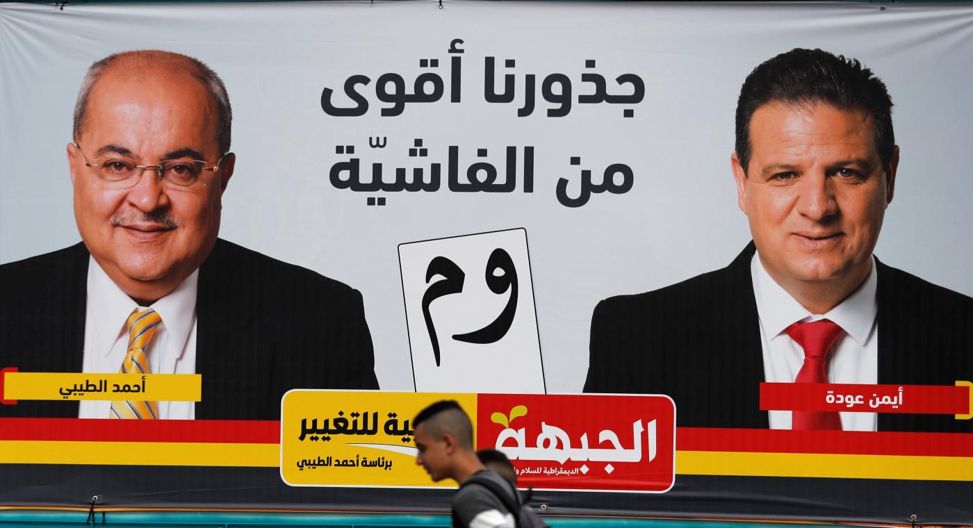 De jeunes citoyens palestiniens d’Israël passent devant une affiche de campagne montrant le candidat de Taal Ahmad Tibi (à gauche) et celui du parti communiste Ayman Odeh, le 4 avril 2019 (AFP)