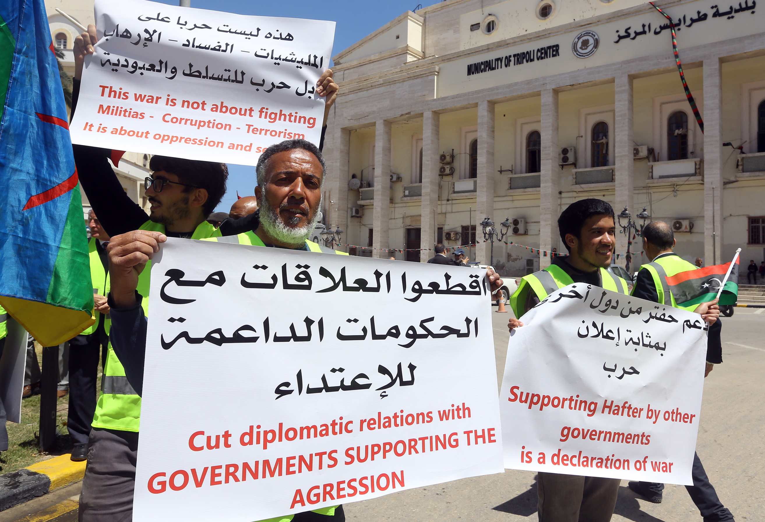 Des manifestants libyens tiennent des pancartes contre ce qu’ils appellent une intervention étrangère en Libye, lors d’une manifestation devant la mairie de Tripoli, le 16 avril 2019 (AFP)