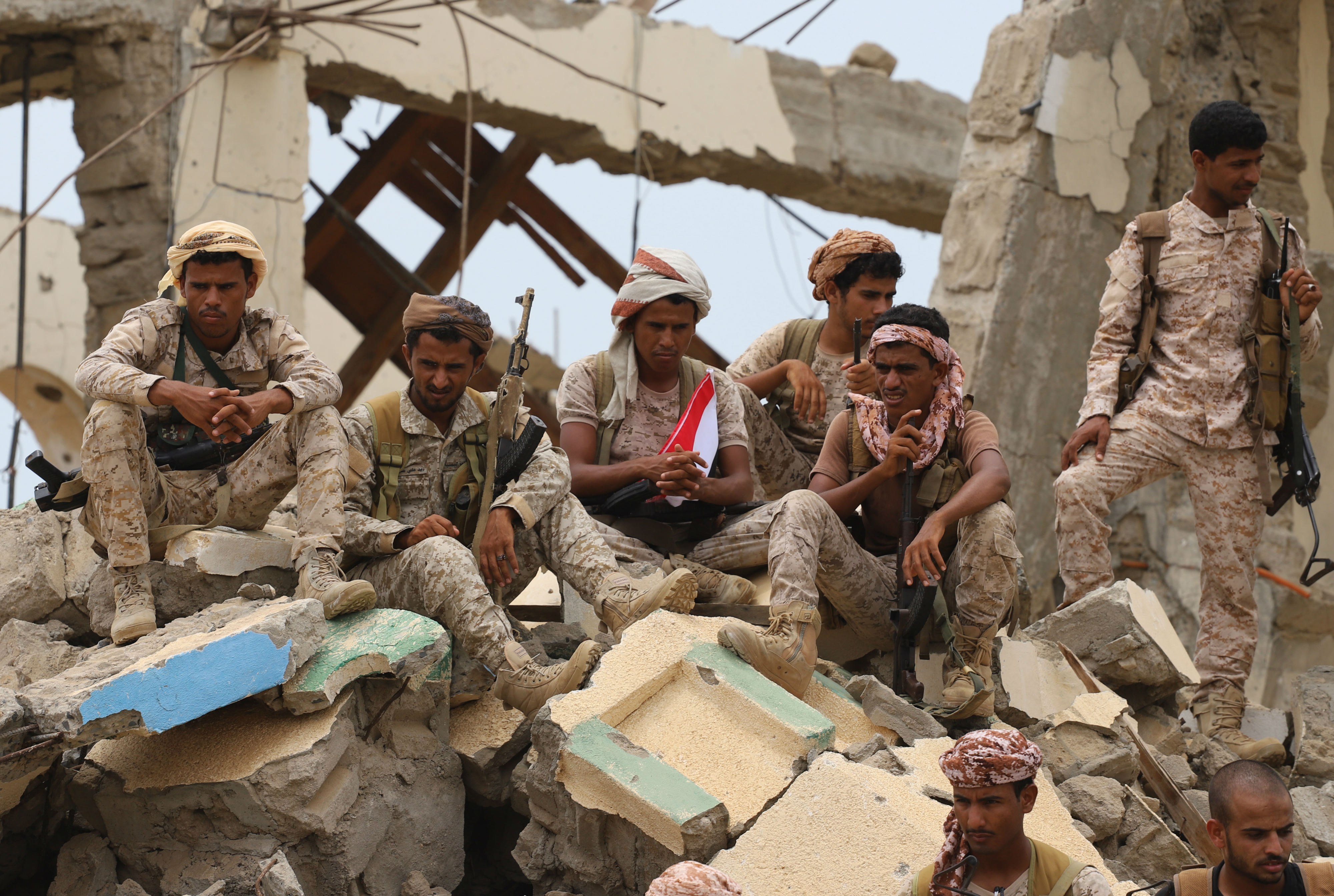 Saudi-backed Yemeni fighters gather above debris of a building in Midi (AFP)