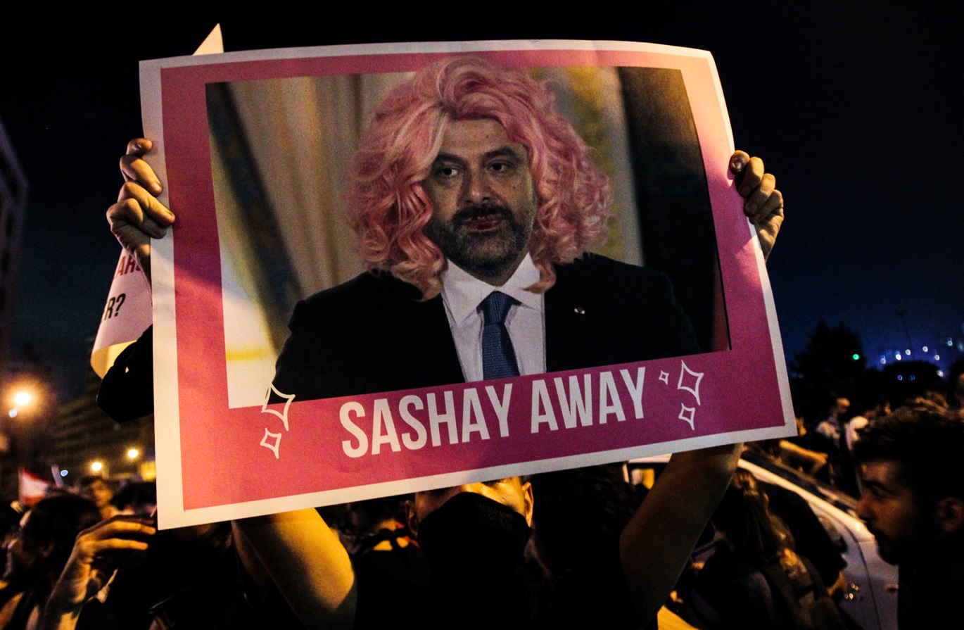 Un manifestant libanais brandit une pancarte avec la photo du Premier ministre Saad Hariri flanqué d’une perruque lors d’un rassemblement dans le centre-ville de Beyrouth, le 19 octobre 2019. « Sashay qway » fait référence à une série télévisée et signifie « pars » (AFP)