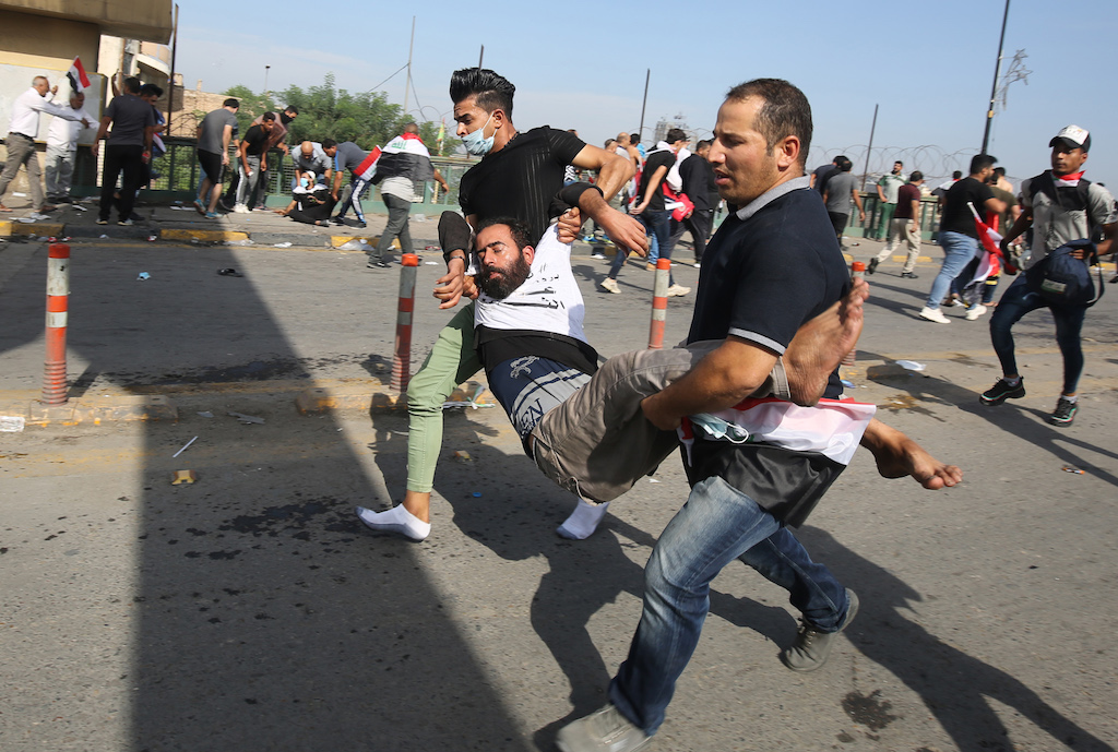 Iraqi protesters carry a comrade who fainted due to tear gas used by security forces to disperse the crowds in central Baghdad during anti-government demonstrations in the Iraqi capital
