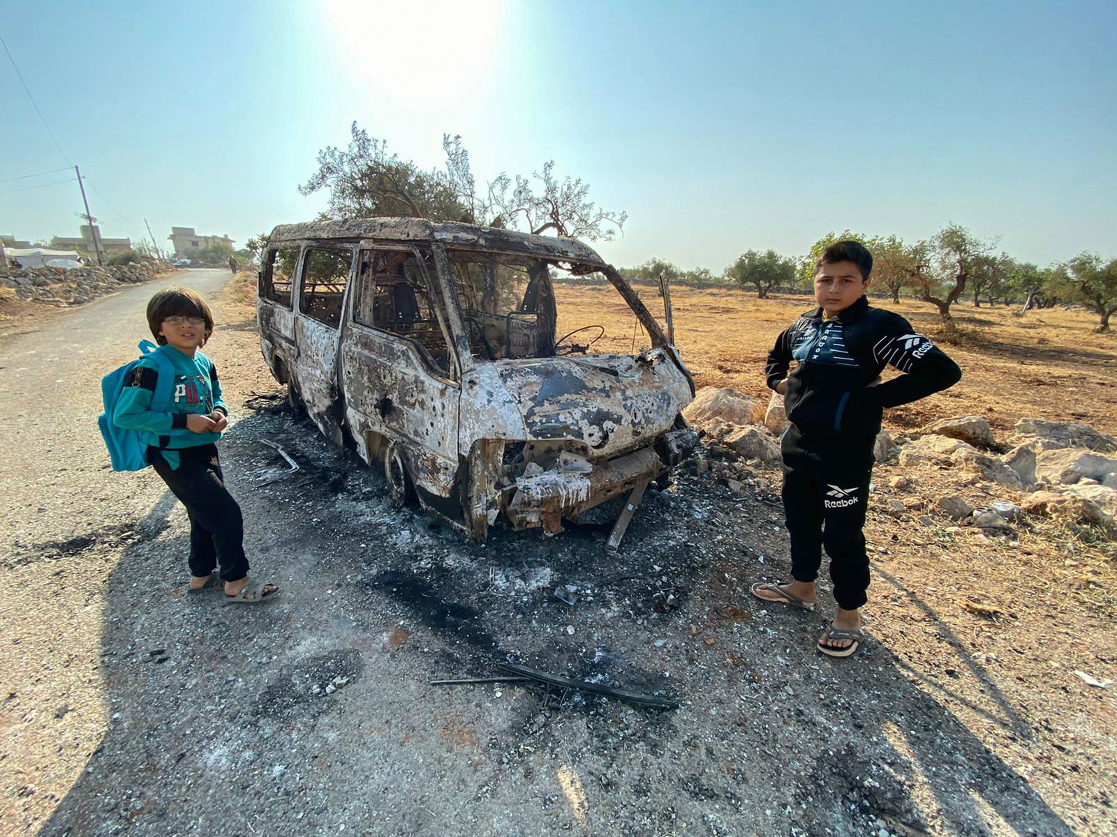 Syrian children stand next to a burnt vehicle near the site where a US raid targeted Baghdadi (AFP)