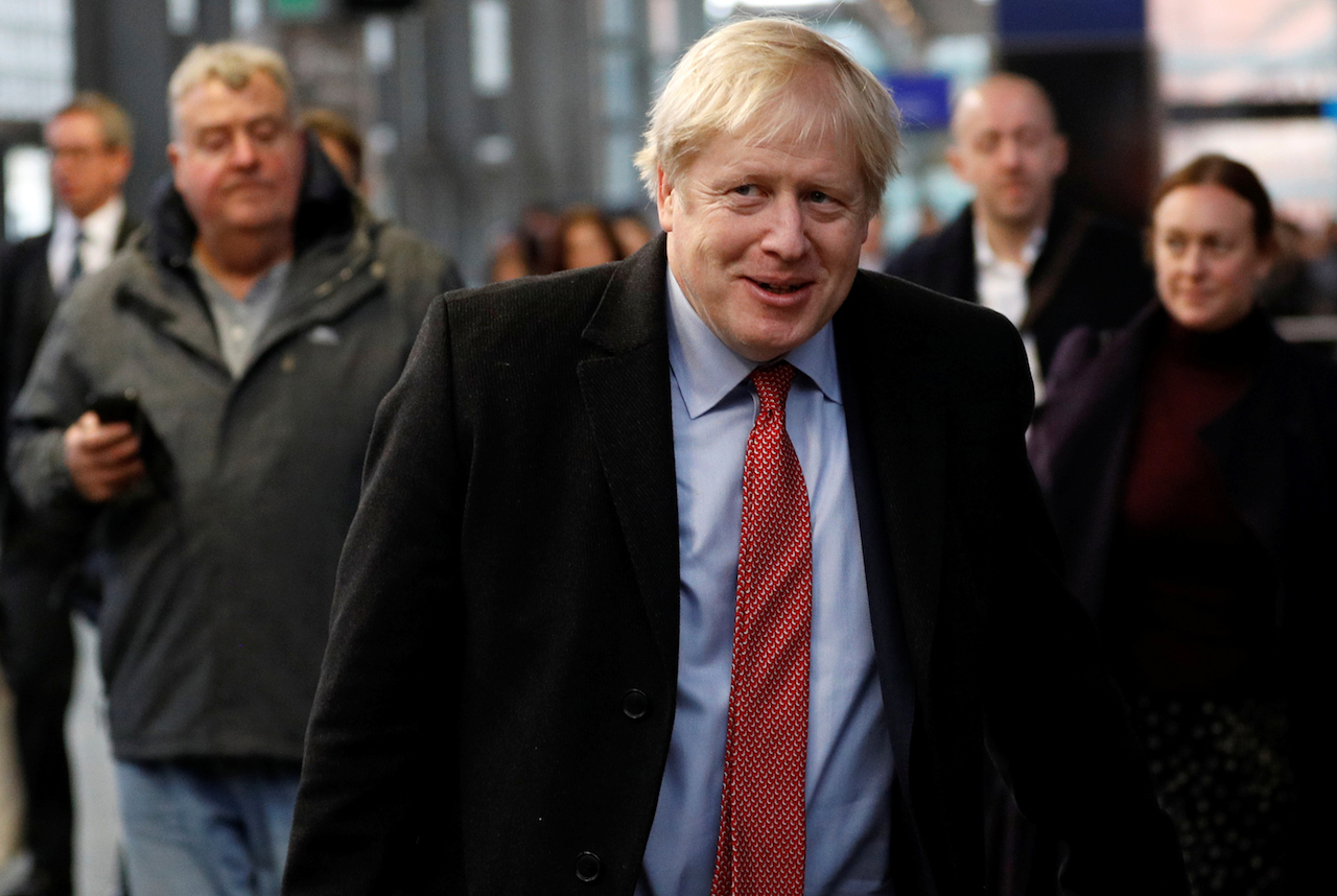 Britain's Prime Minister Boris Johnson reacts as he walks along a platform to board a train ahead of a Conservative Party general election campaign visit, at St Pancras station in London (AFP)