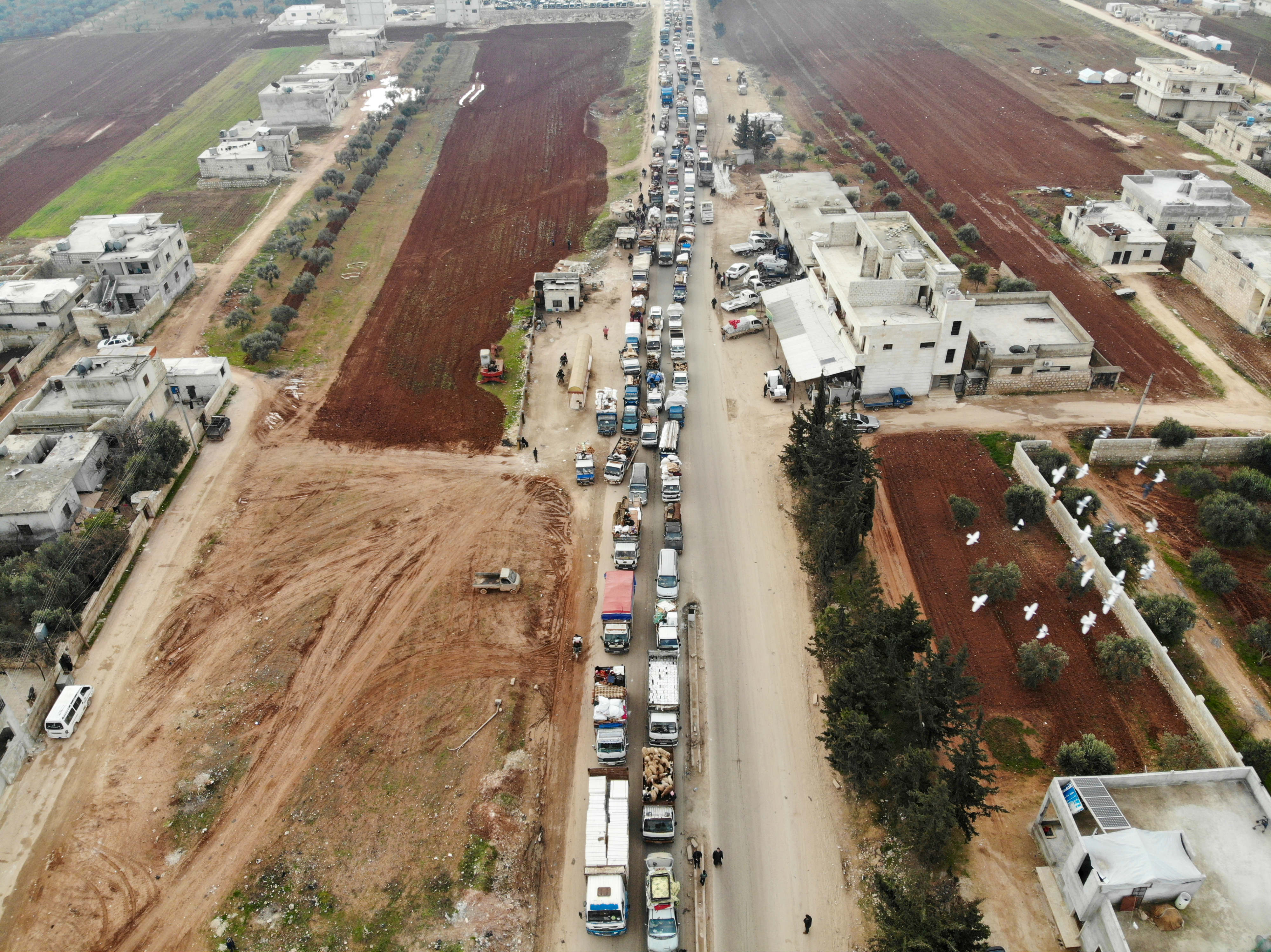 A aerial photo shows displaced Syrians driving through Hazano in the northern countryside of Idlib, after fleeing on 28 January (AFP)