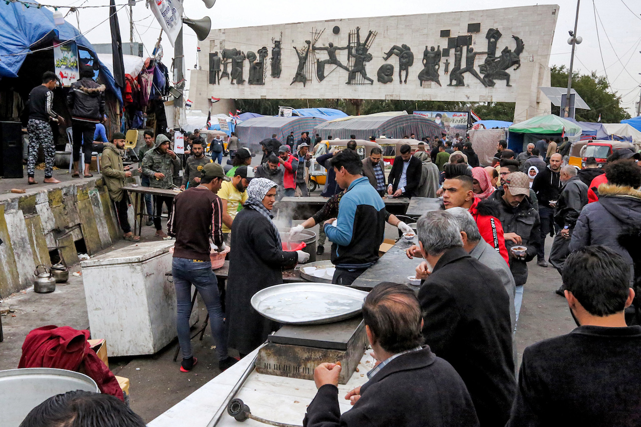 People cook and distribute food at the anti-government protest sit-in in the Iraqi capital Baghdad's central Tahrir Square. The Freedom Monument overlooks the square (AFP)