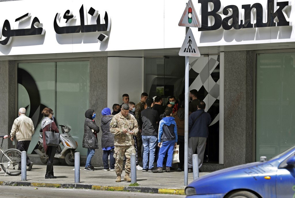 Des Libanais attendent devant une banque pour récupérer leurs salaires le 31 mars 2020 dans la ville côtière de Tripoli (AFP)