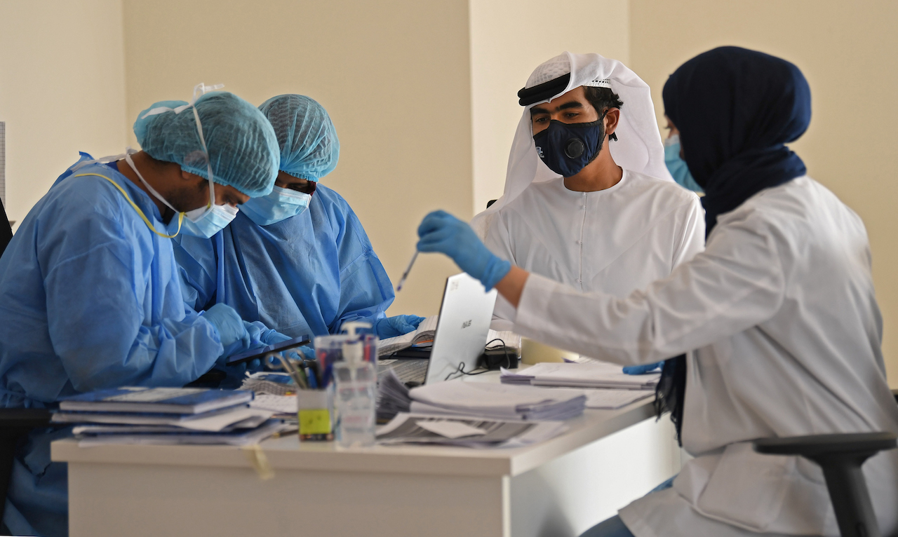 Health workers gather a centre in the Warsan neighbourhood, where people infected or suspected of being infected by the virus are quarantined, in the Gulf Emirate of Dubai (AFP)