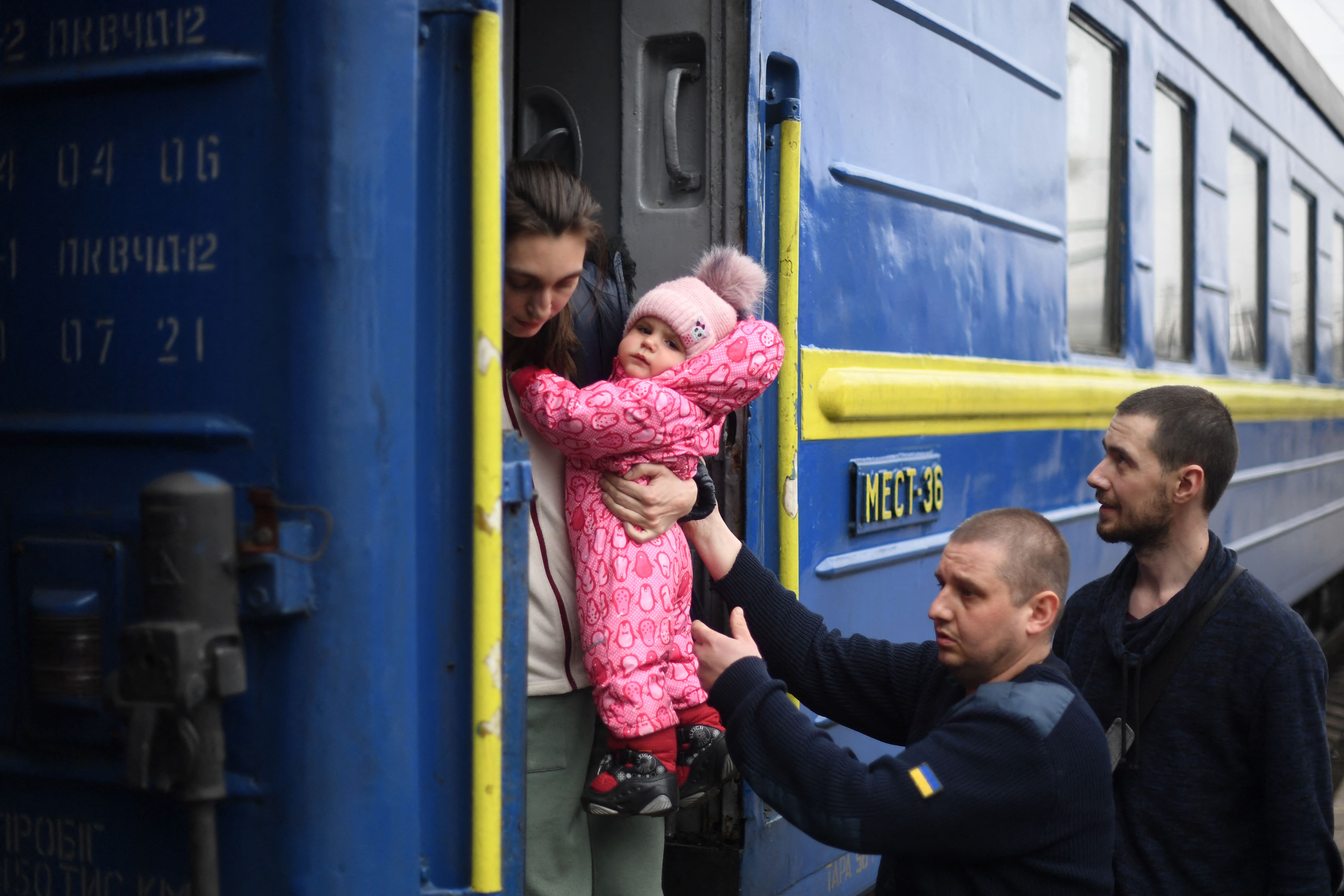 A woman holds her child as she arrives from Odessa at a train station in Lviv, western Ukraine, on 3 March 2022. (AFP)