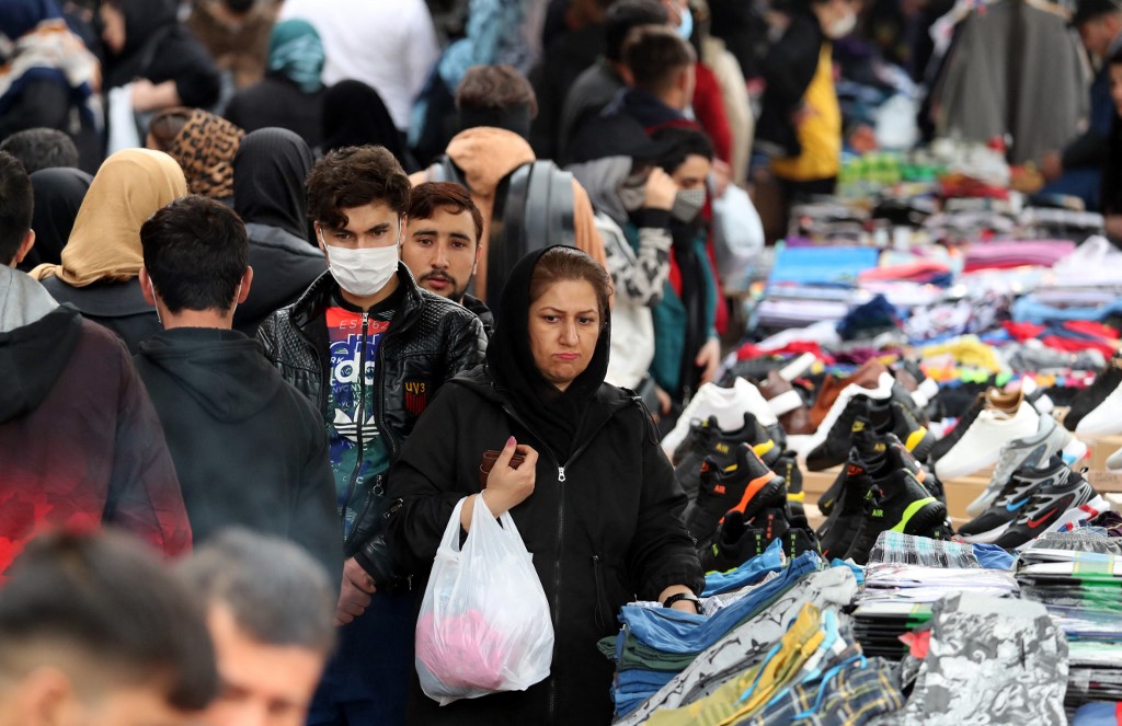 Iranians shop on a market street in the capital Tehran, on 11 March 2022 (AFP)