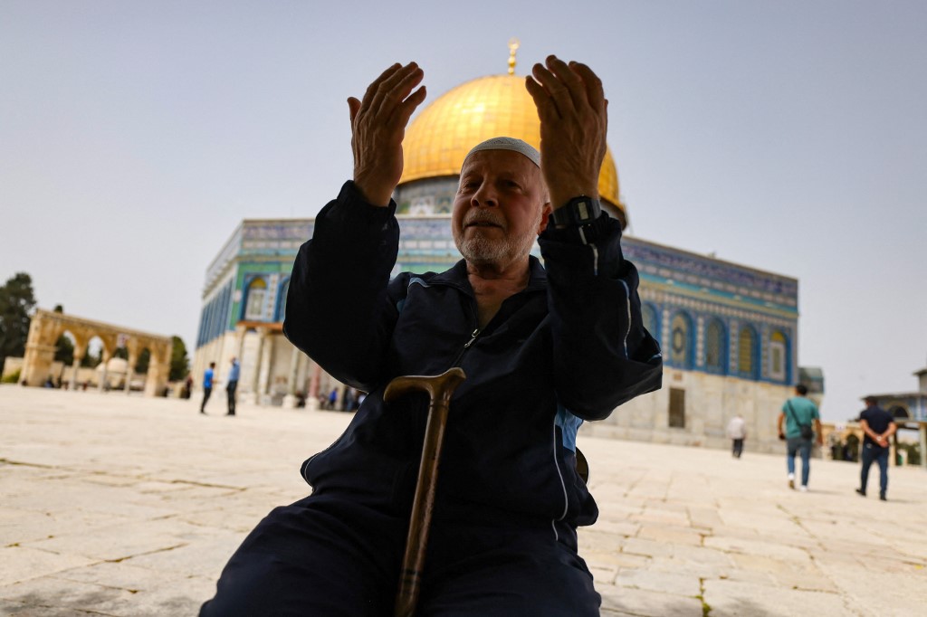 A Palestinian man prays in front of the Dome of Rock at the al-Aqsa Mosque after a raid by Israeli forces and settlers on 17 April 17 2022. (AFP)