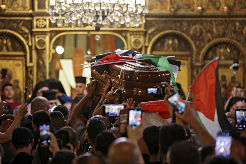 Palestinian mourners wave national flags as they carry the casket of Abu Aklel inside a church before her burial in Jerusalem. (AFP)
