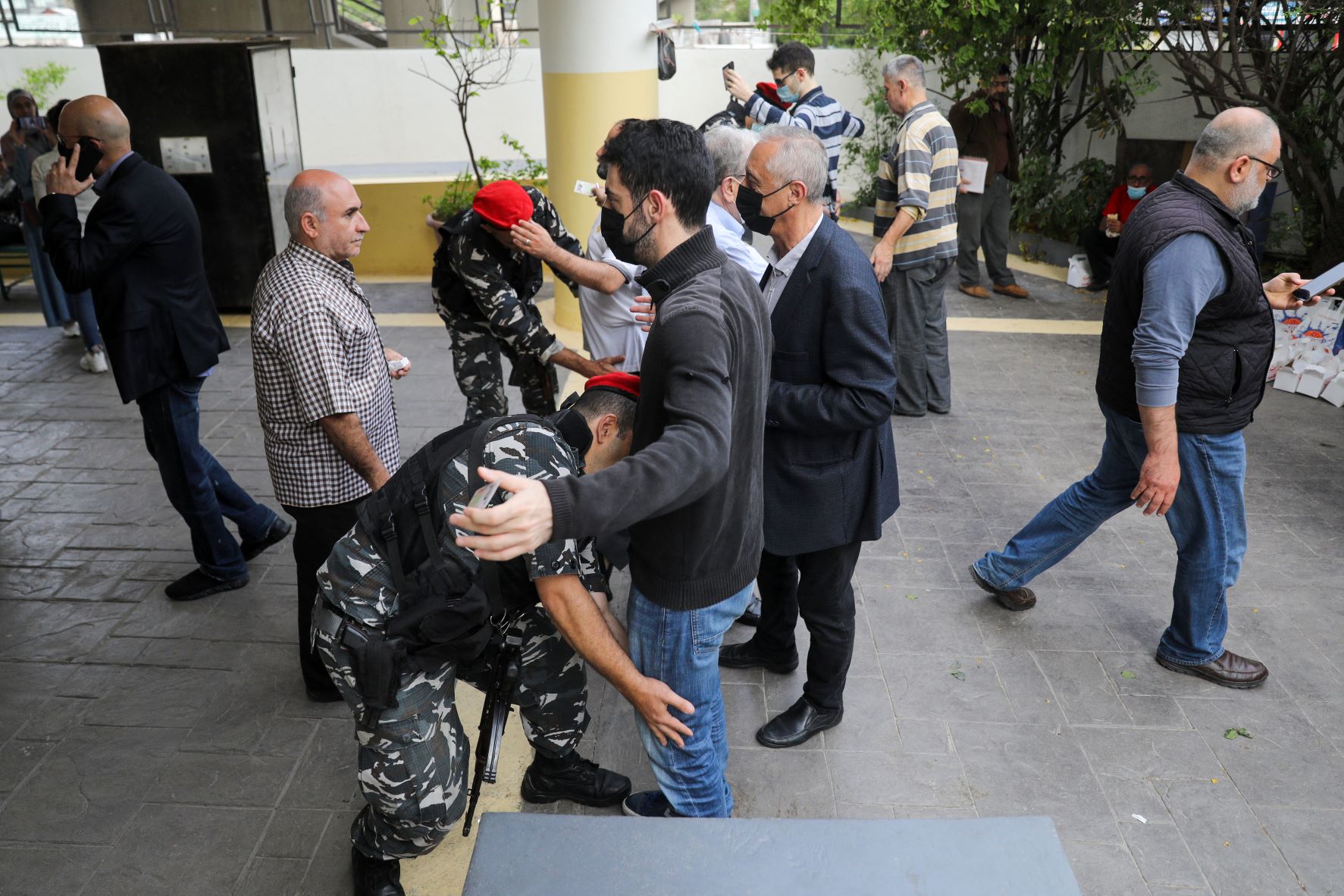 Policemen frisks voters outside a polling station in the Lebanese capital Beirut, on May 15, 2022 (AFP)