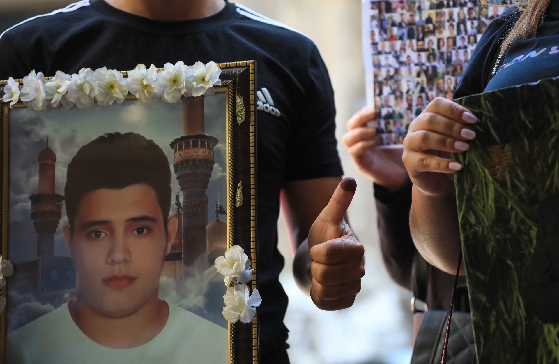 Families of victims of the 2020 Beirut port explosion carry portraits of their relatives outside of a polling station in Beirut (AFP)