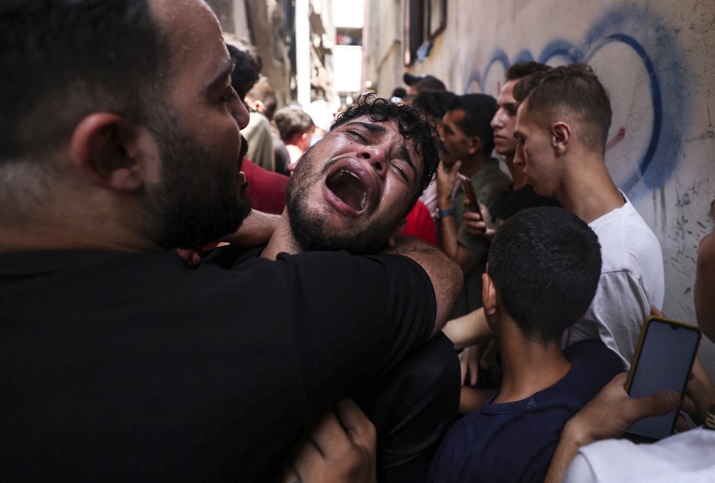 The friend of a young Palestinian killed during the night in the Jabalia refugee camp in the northern Gaza Strip, reacts during his funeral in the same camp, on 7 August 2022 (AFP)