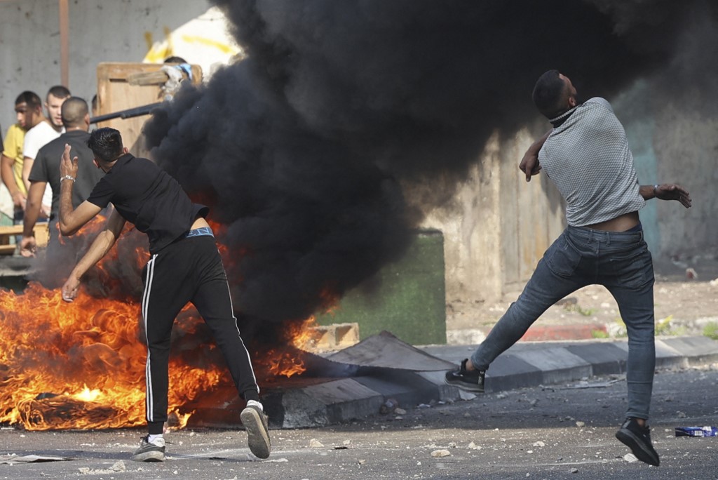 Palestinian protesters hurl stones at Israeli forces after a raid in the old town of Nablus, in the occupied West Bank, on 9 August 2022. (AFP)