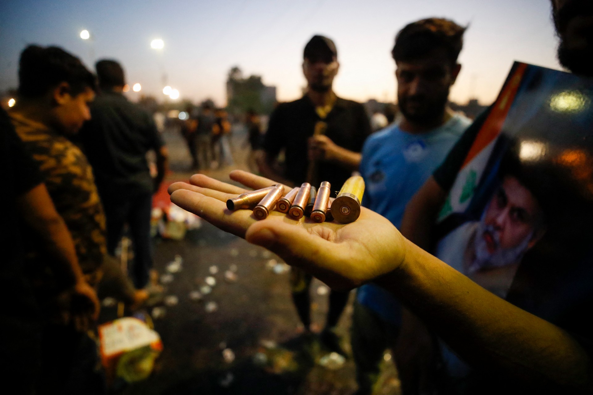 A Sadrist carries bullet casings and a spent shotgun shell in Baghdad (AFP)