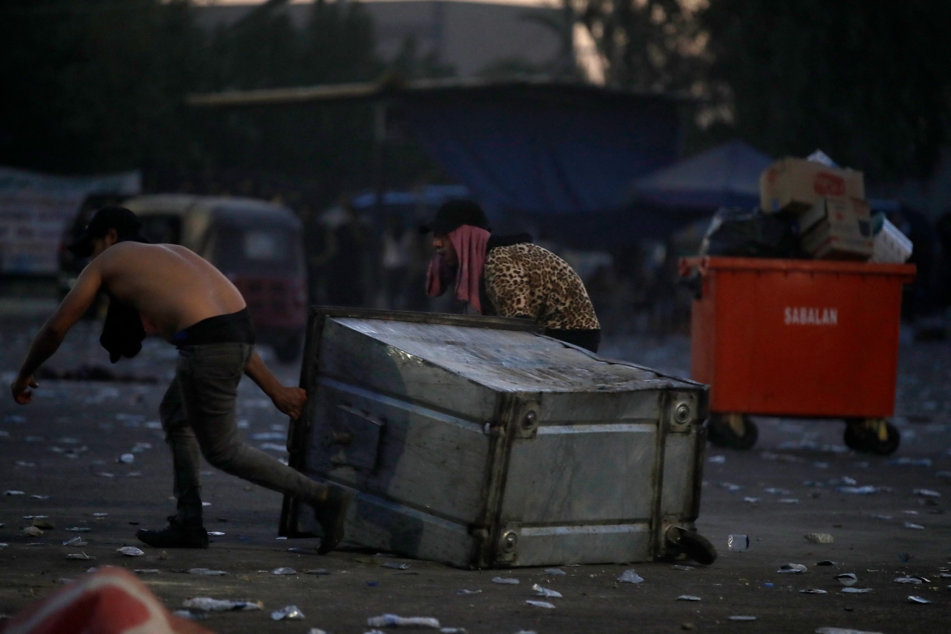 Supporters of Sadr drag a bin to use as cover in Baghdad (AFP)