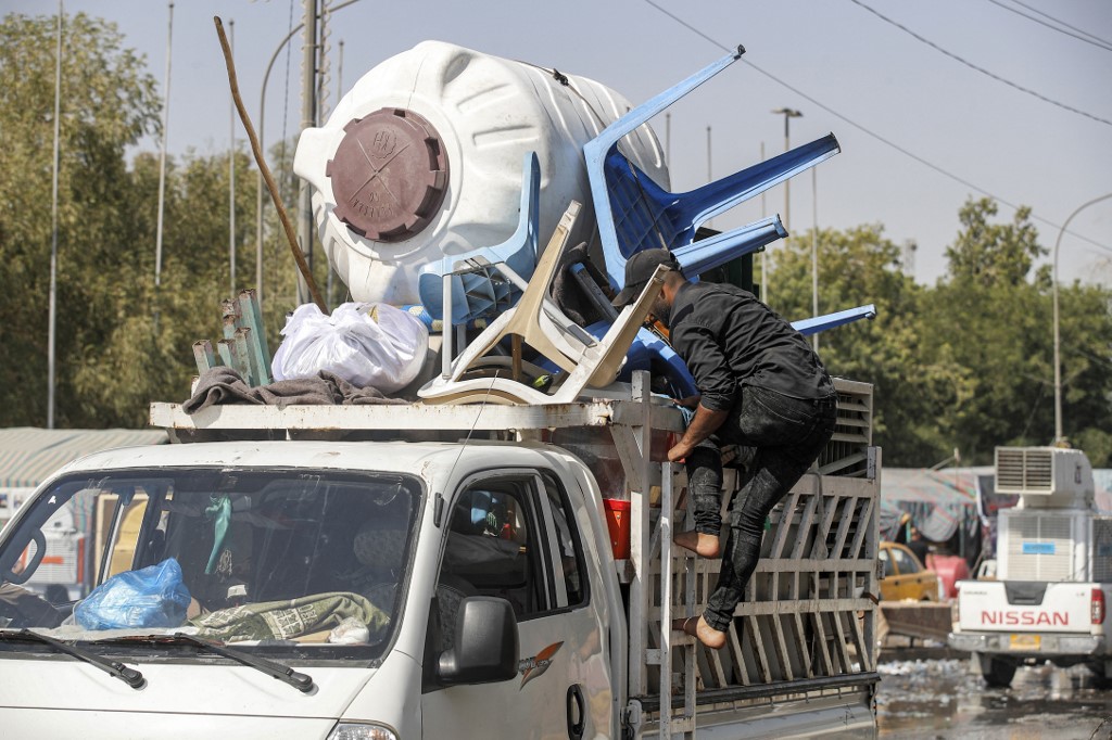 Plastic chairs and a water cistern used by supporters of Muqtada al-Sadr are transported away as their encampment in the Green Zone is dismantled on 20 August 2022 (AFP)