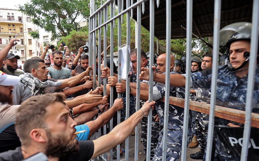 Protesters try to pull out the gate leading to the Justice Palace in Lebanon's capital Beirut on September 19, 2022, demanding the release of two people involved in a bank heist the prior week (AFP)