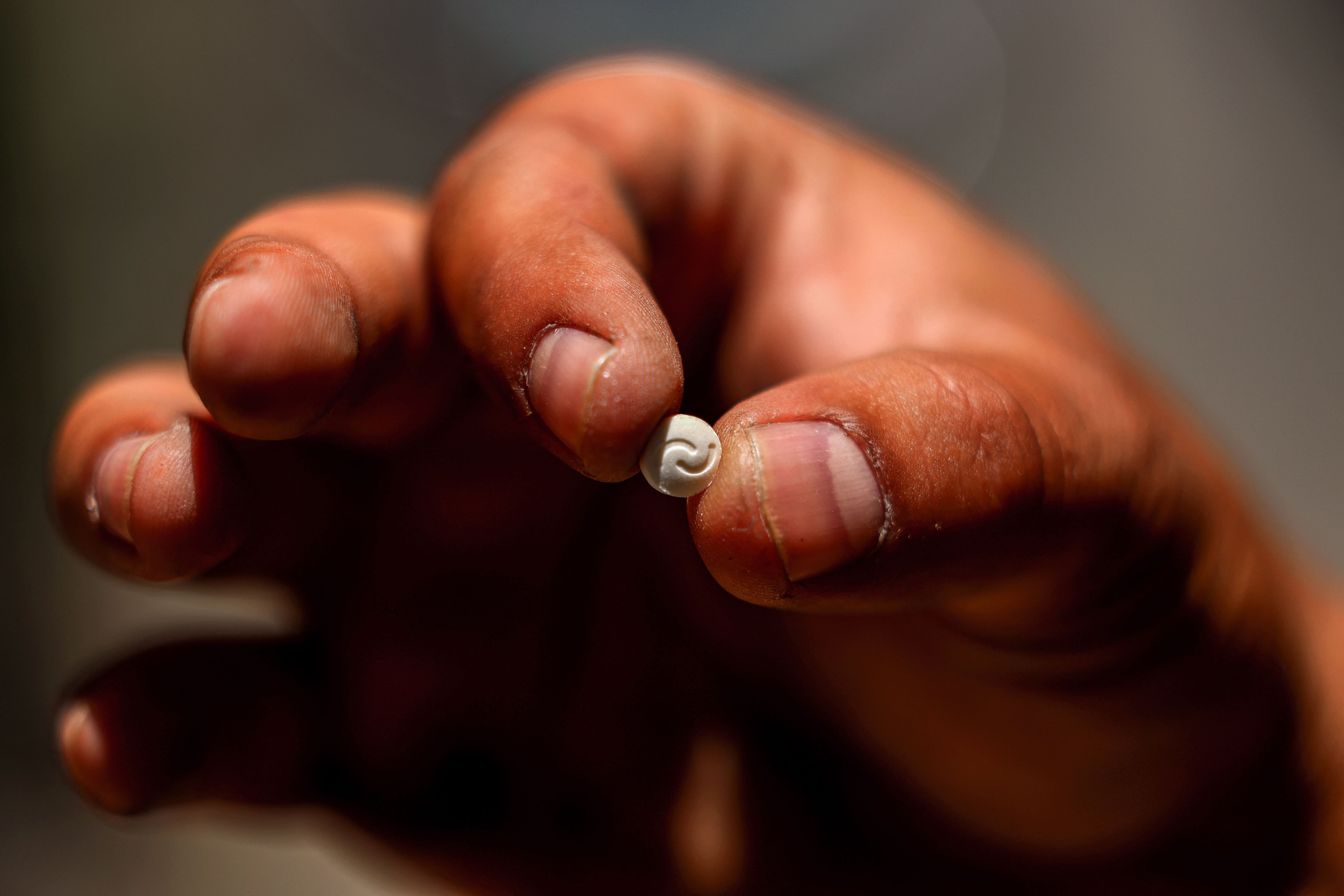 A Lebanese security official holds a single confiscated captagon pill in his hand at the judicial police headquarters in the city of Zahle in Lebanon's central Bekaa valley on July 21, 2022 (AFP)