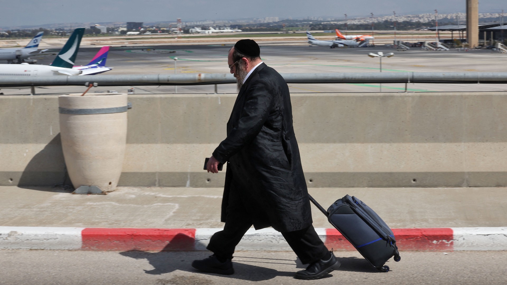 A man walks towards the departures area of Ben Gurion Airport as demonstrators block the main road on 9 March (AFP)
