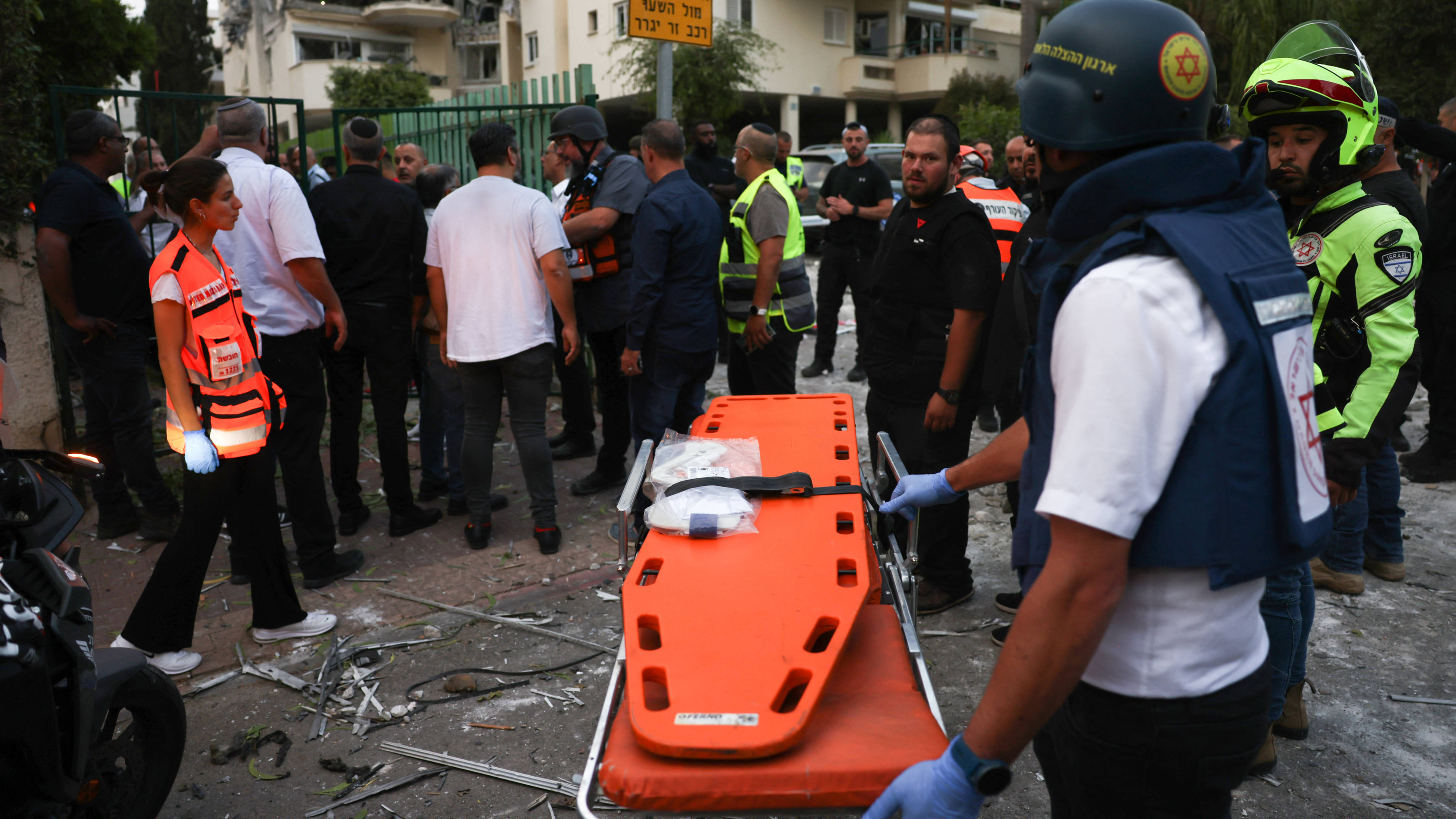 Rescuers wait with a stretcher in front of a building hit by a rocket fired from the Gaza strip, in Rehovot near Tel Aviv, on 11 May 2023 (AFP) 