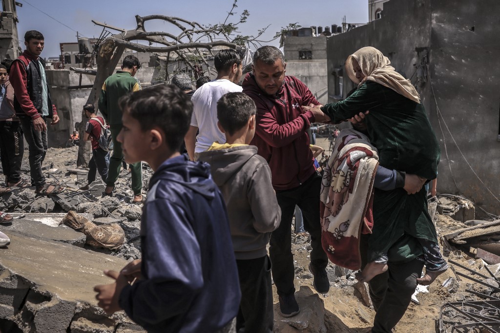People carry away an elderly woman following an Israeli air strike in Beit Lahia in the northern Gaza Strip, on May 13, 2023. 