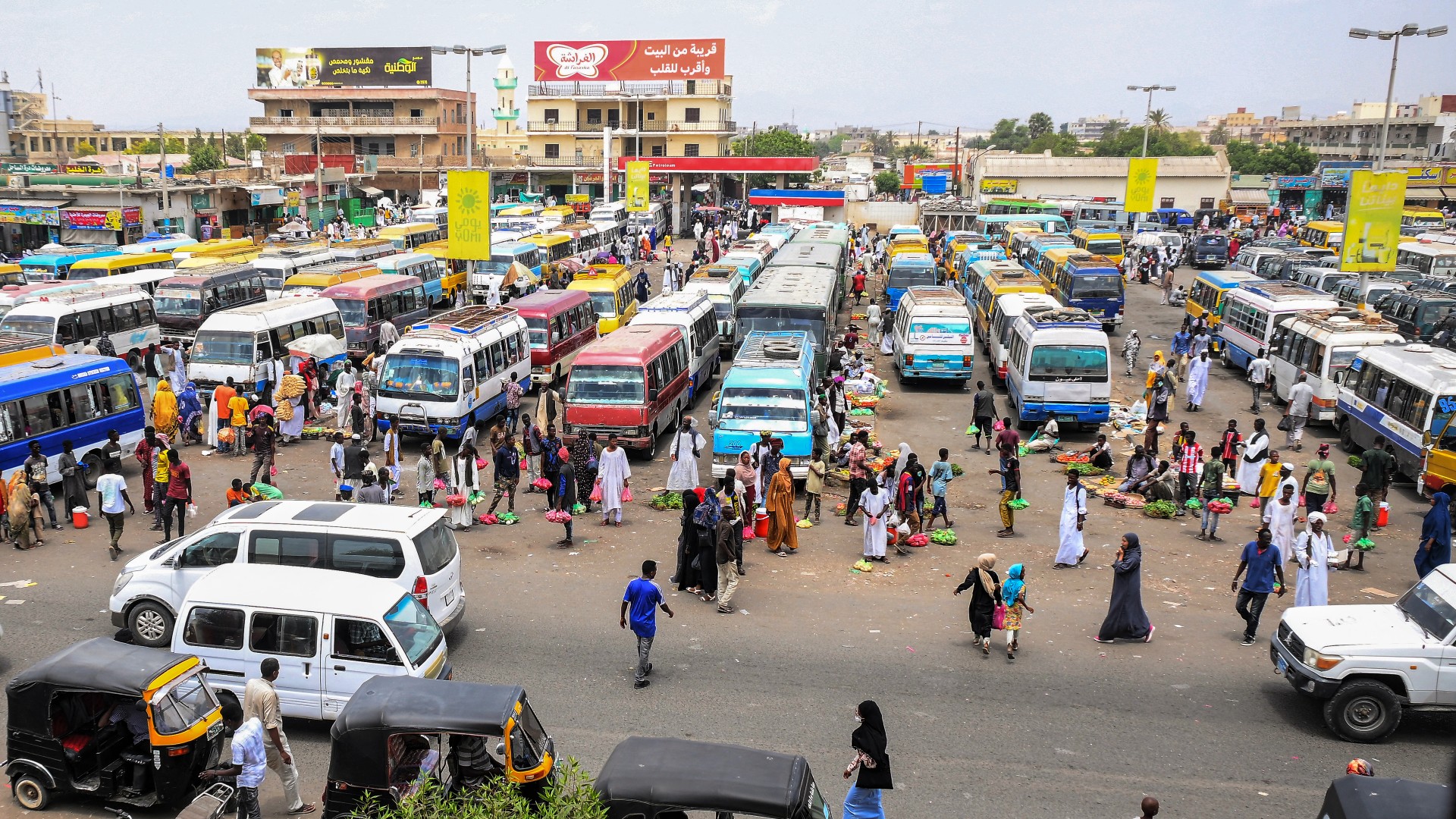 Produce vendors wait by buses and tuk-tuks for customers and passengers at a bus station in Port Sudan on 23 May (AFP)