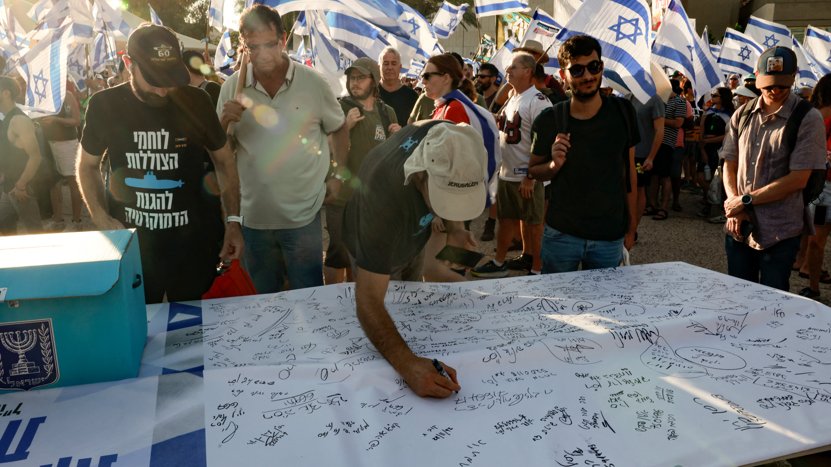 Israeli military reservists sign a declaration announcing the suspension of their voluntary duty in Tel Aviv on 19 July 2023 (AFP)