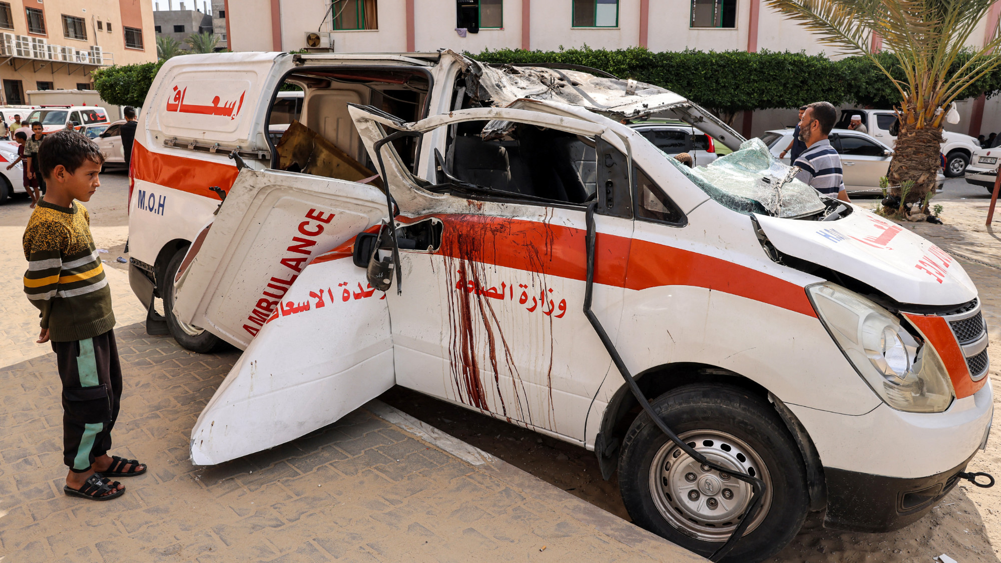 Children view a destroyed ambulance parked along a street in Khan Yunis in the southern Gaza Strip on 11 October 2023 (AFP)