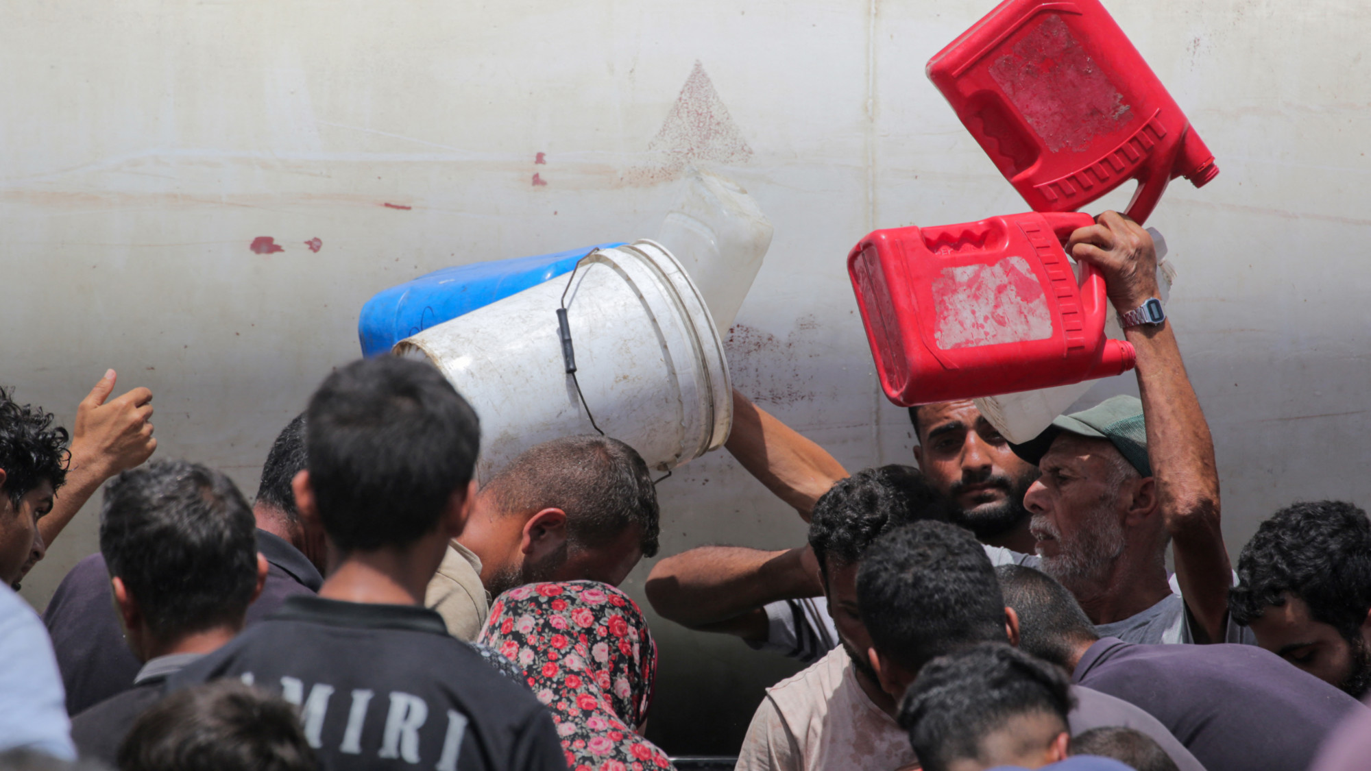 Displaced Palestinians queue for water at a camp west of Deir al-Balah in the Gaza Strip on 21 May 2024 (AFP)