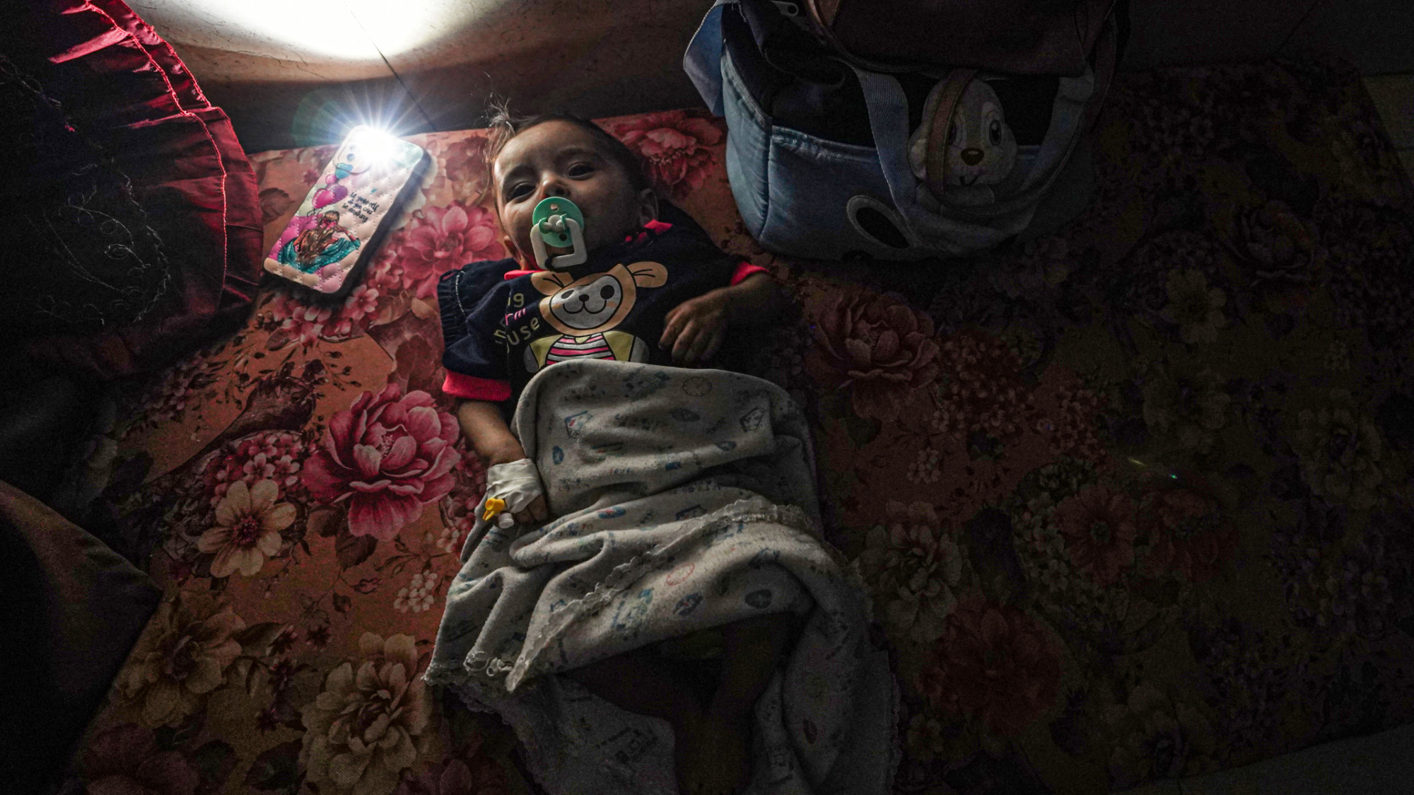 A baby lying on the floor after a partial power cut at the al-Aqsa Martyrs hospital in Deir al-Balah on 23 May 2024 (AFP/Bashar Taleb)
