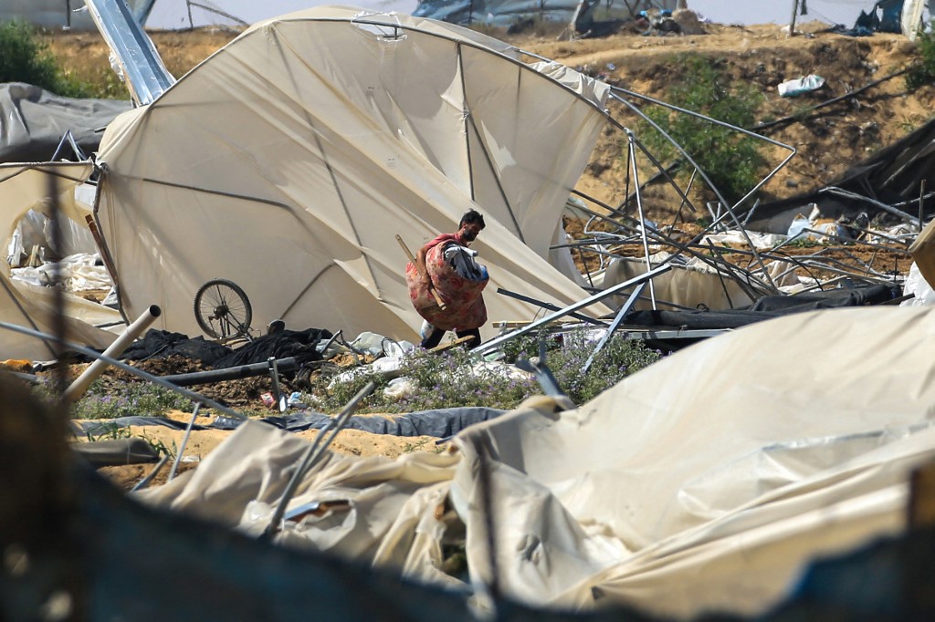 A man carries salvaged items following an Israeli raid in al-Mawasi area Rafah, on the southern Gaza Strip on June 29, 2024,