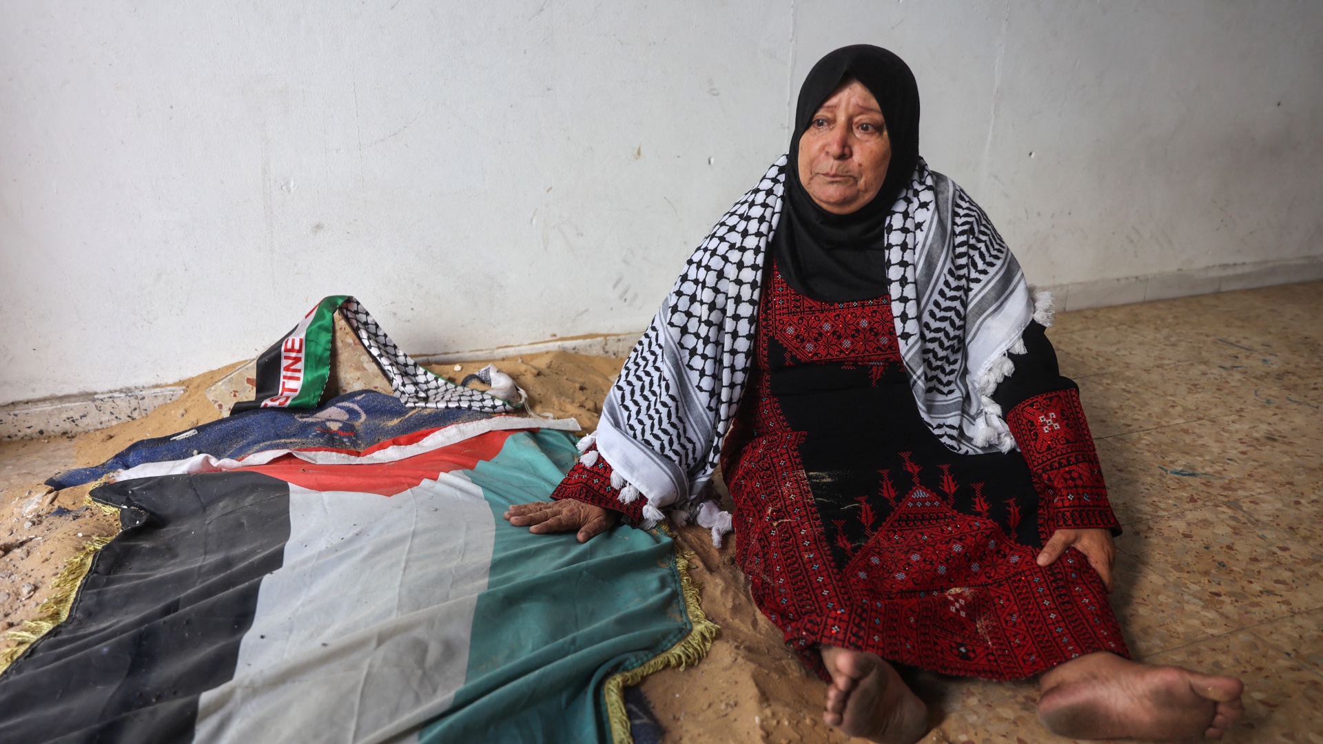 Maryam Abu Obeid, 65, mourns while sitting by her grandson Khaled's makeshift gravesite at their home in Gaza City's Sheikh Radwan neighbourhood on 7 August (Omar Al-Qattaa/AFP)