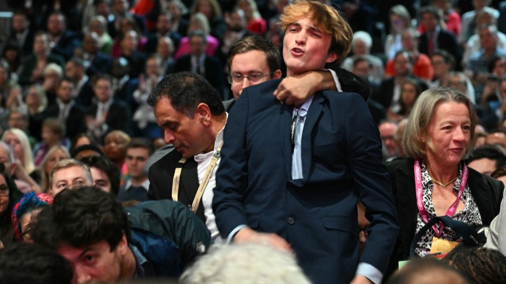 A pro-Palestinian protester is grabbed by the throat during Chancellor Rachel Reeves' speech on Monday