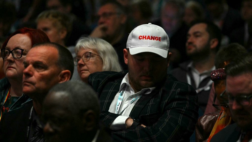 A delegate wears a hat reading 'CHANGE' as they listen to a speaker on the fourth day of the conference