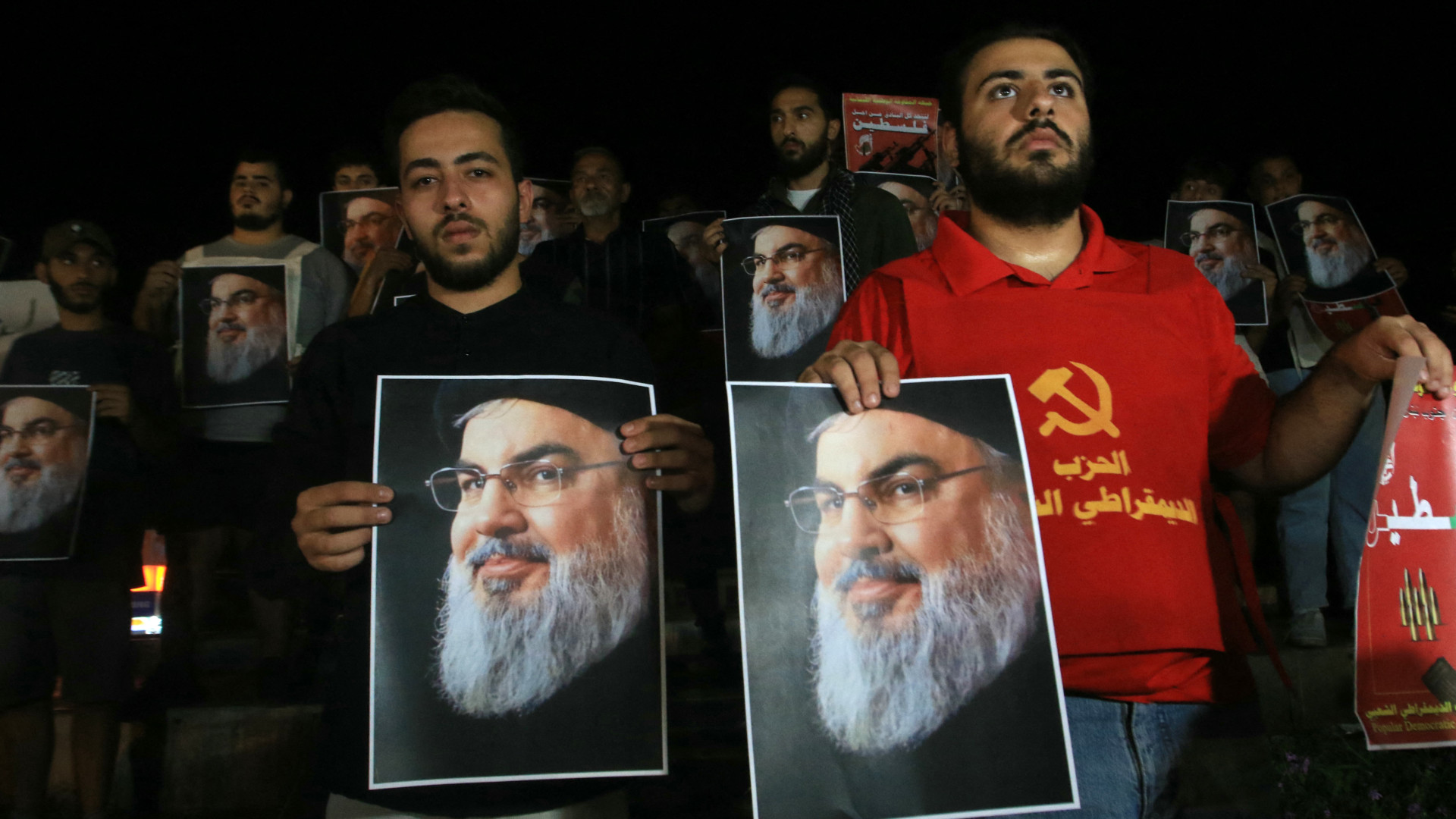 Demonstrators hold pictures of Hassan Nasrallah, late leader of the Lebanese group Hezbollah, during a protest vigil in the southern Lebanese city of Sidon on 28 September 2024 (Mahmoud Zayyat/AFP)